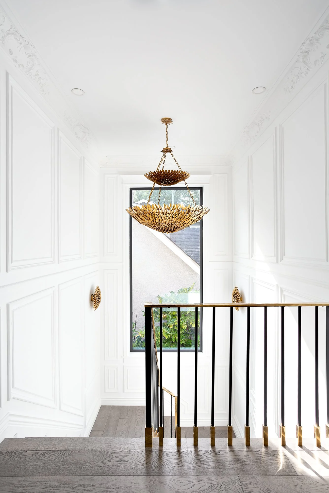 Bright staircase landing with classic white wall paneling and a large, ornate gold