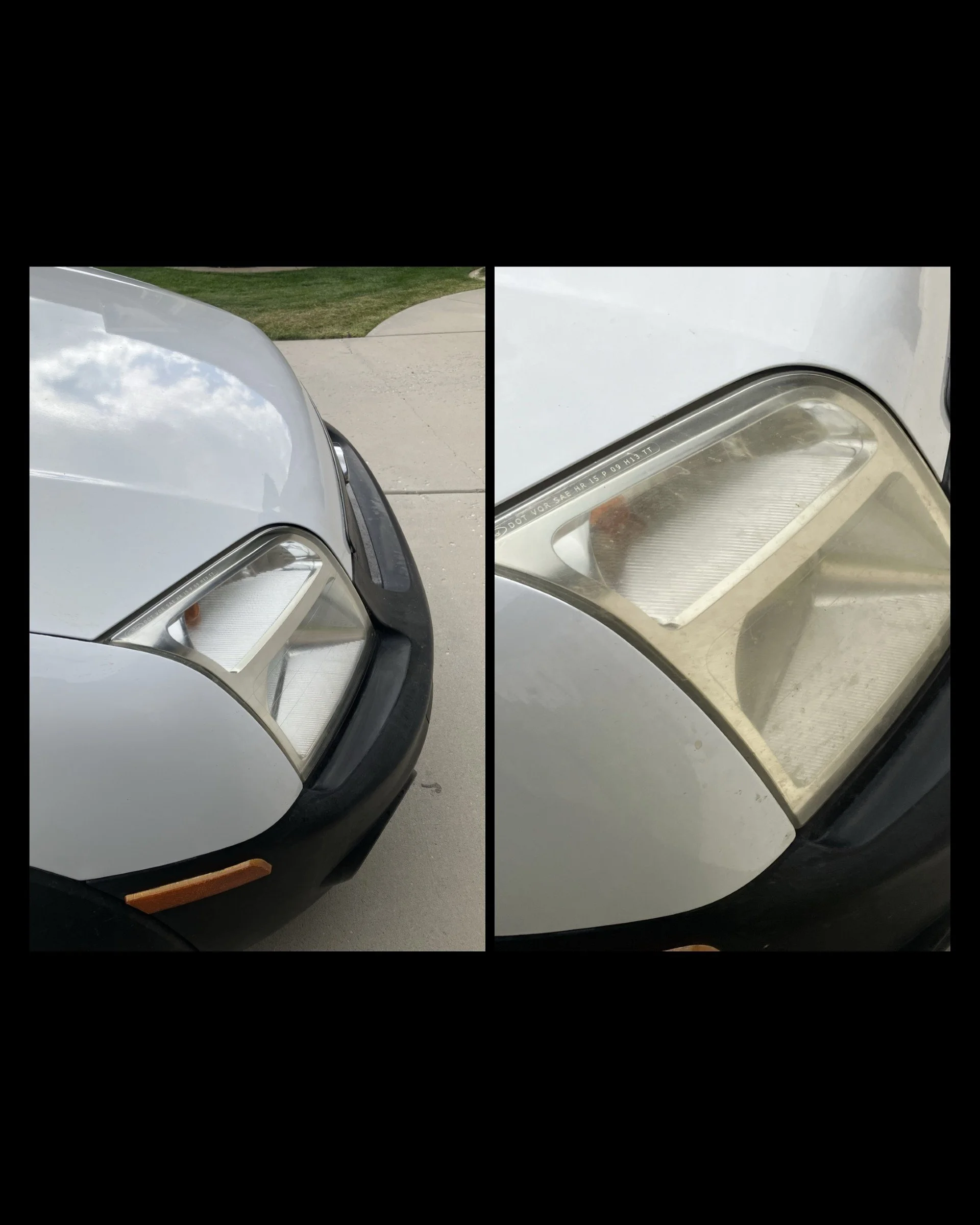 Close-up of the front headlight of a white car, showing the glass cover and surrounding black trim, with a sidewalk and grass in the background.