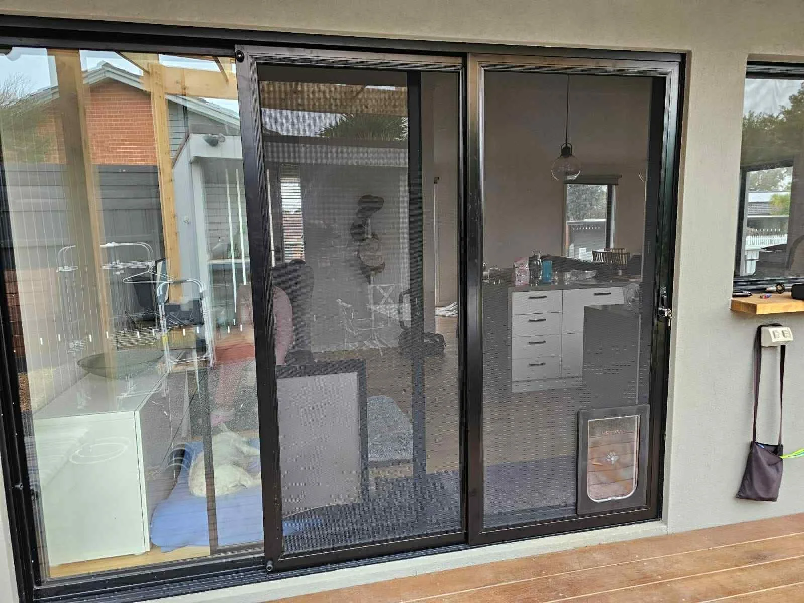Sliding glass door with a view of an interior kitchen and dining area, with outdoor wood deck visible in the foreground.