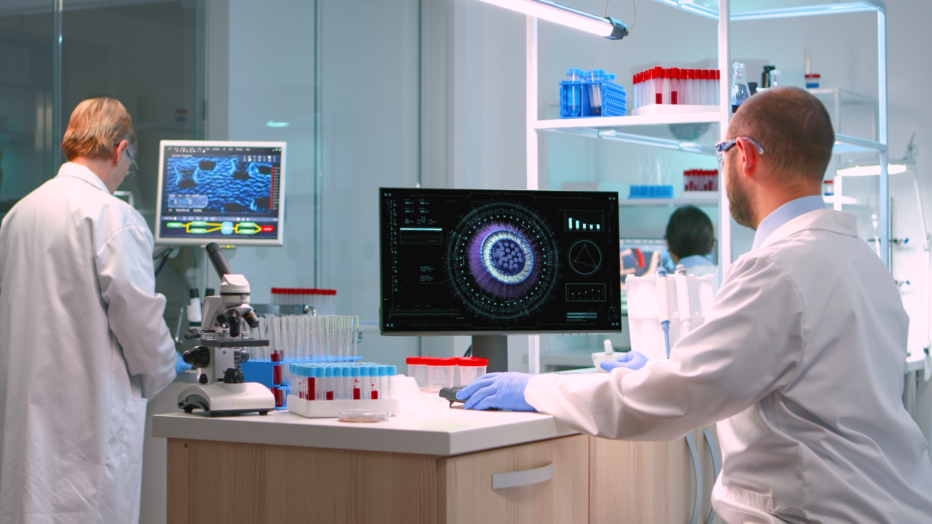 Scientists working in a laboratory with microscopes, test tubes, and computer screens displaying scientific data.