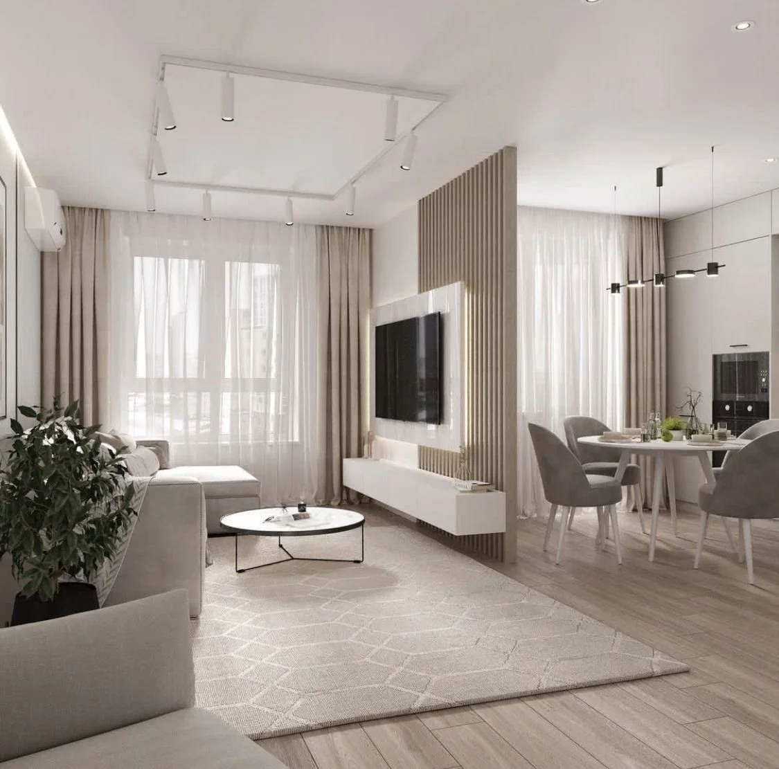 Interno di un soggiorno moderno con divano bianco, tavolino rotondo, parete divisoria con televisore e zona pranzo con tavolo rotondo e sedie grigie, luce naturale e tende beige.