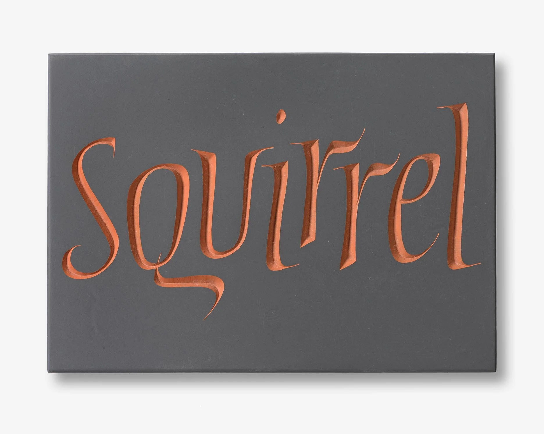 Close-up of a gray wall art piece with the word 'Souled' written in raised, orange, cursive-style letters.