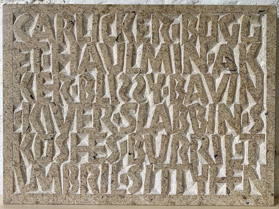 A stone tablet with engraved ancient Greek alphabet characters.
