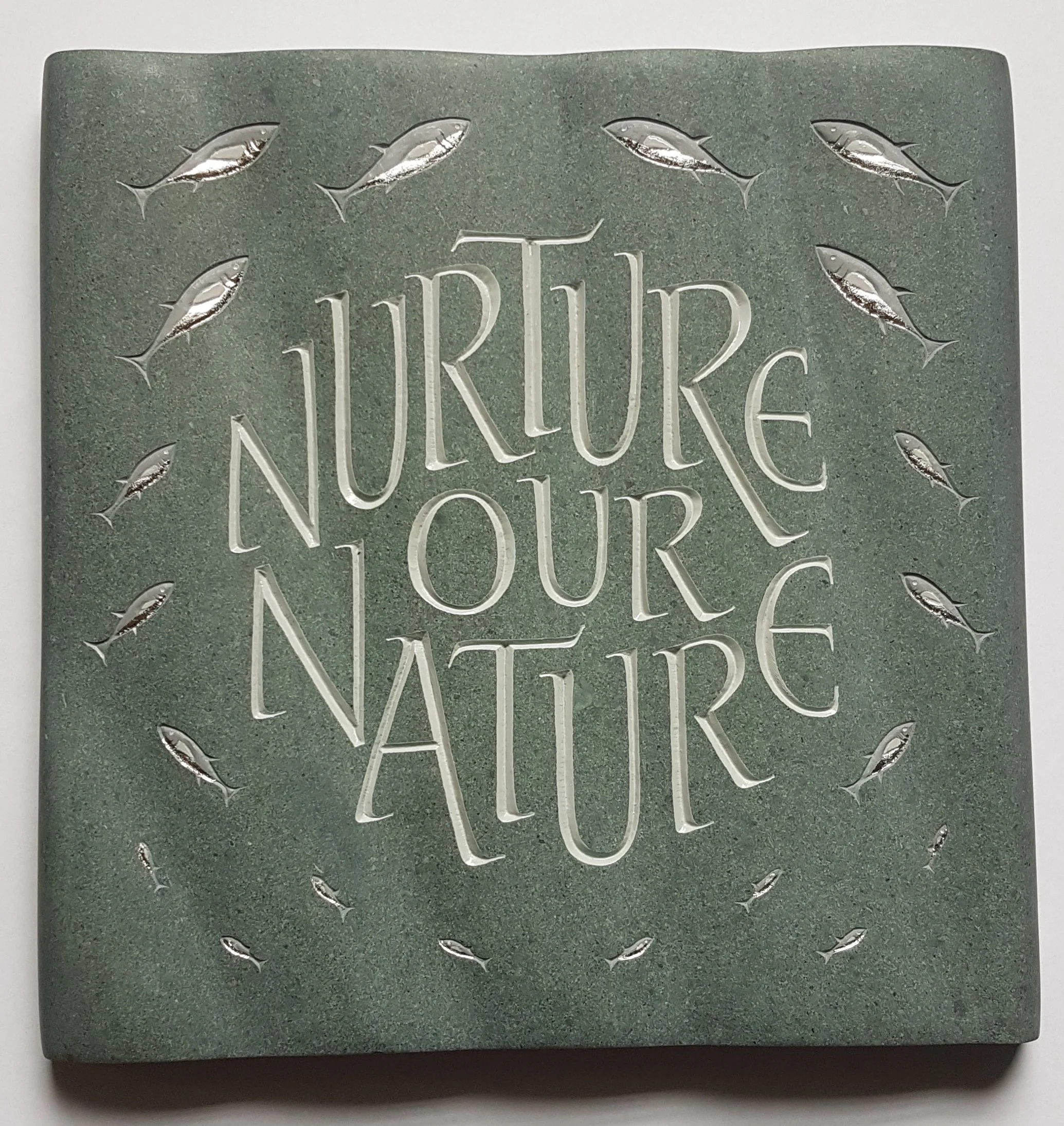 Decorative stone tile with engraved fish and the words 'PIRATE NATURE' in stylized lettering