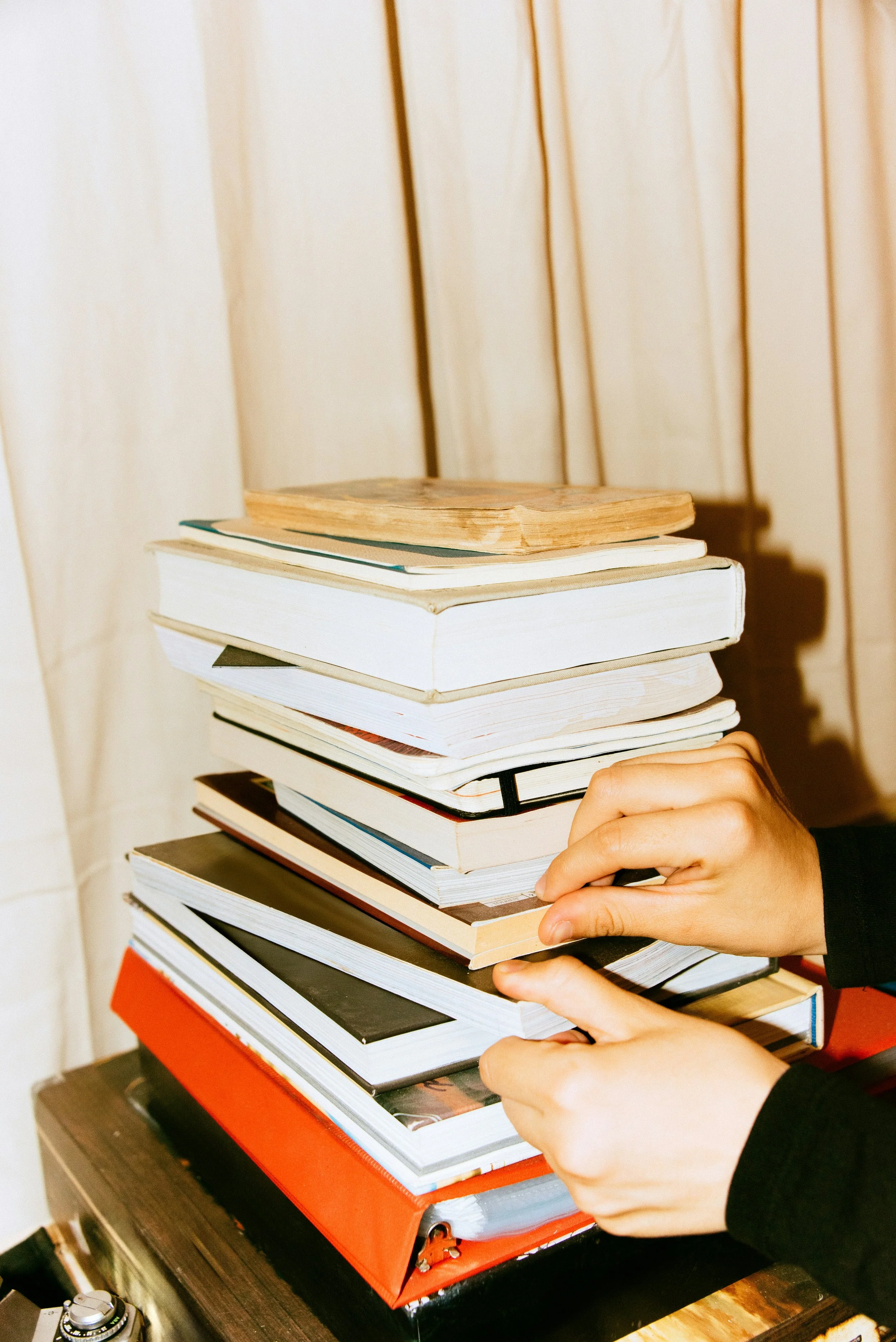A stack of books with hands in the foreground