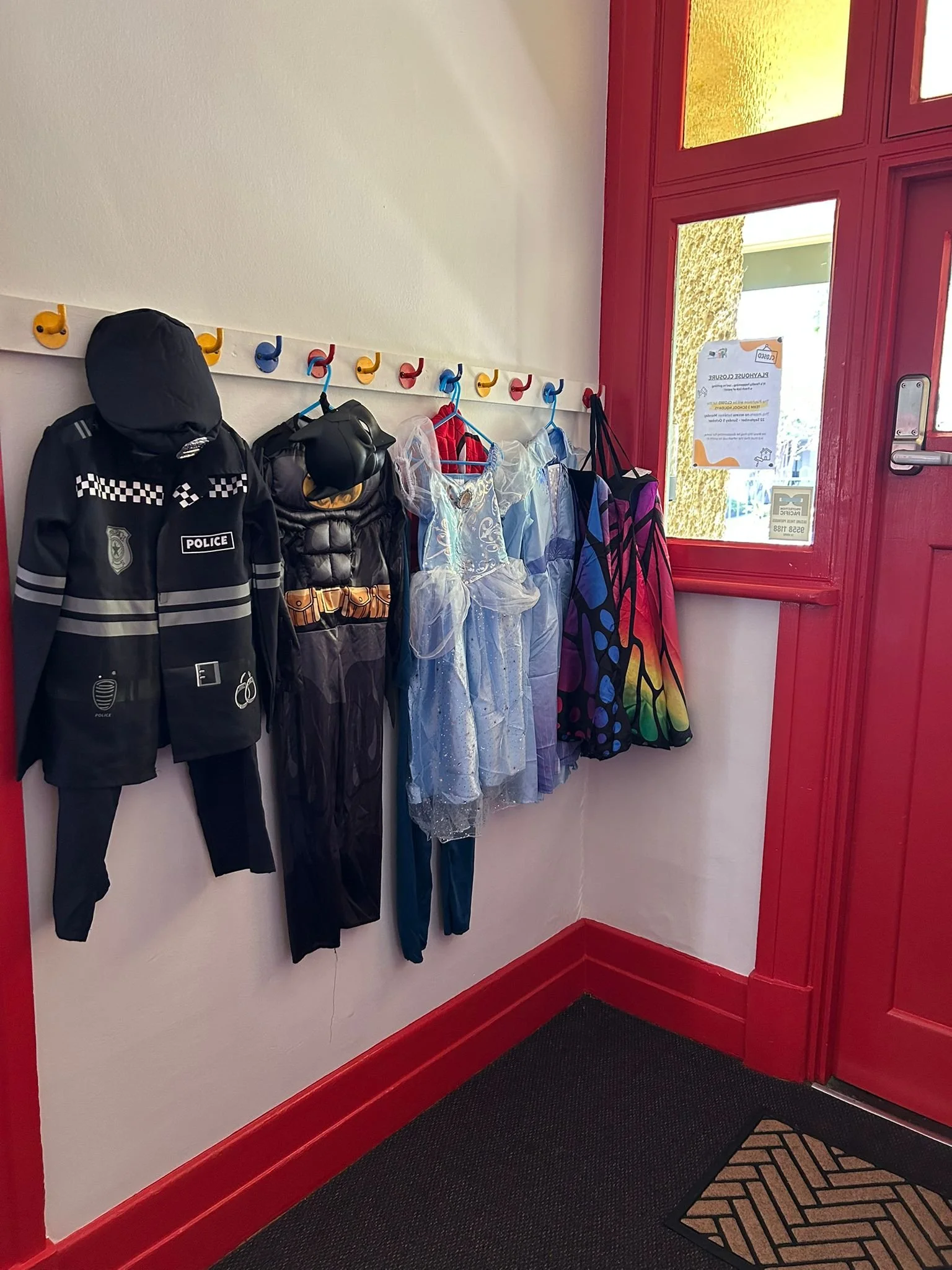 A series of children's costumes hanging on a wall rack.