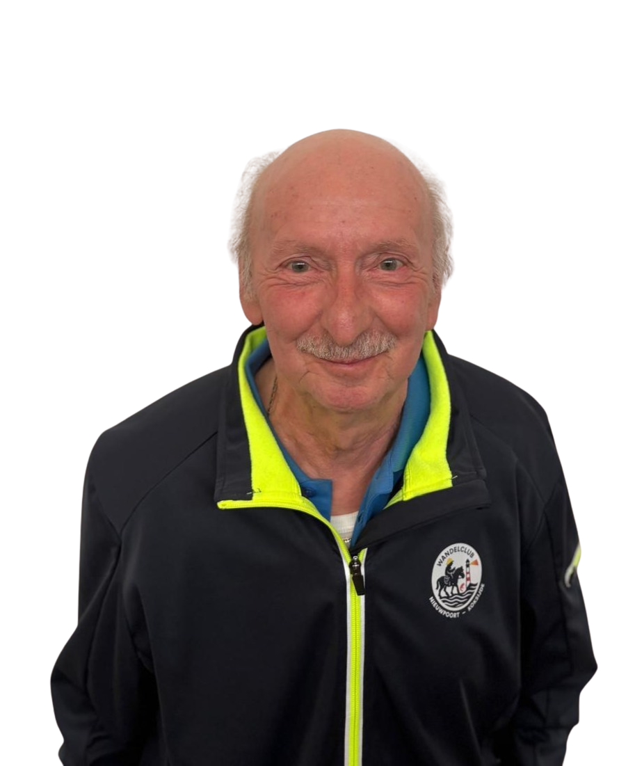 Een oudere man met een glimlach, zittend of staand, tegen een zwarte achtergrond, draagt een zwart jack met opvallende gele rits en een logo van een wandelclub.