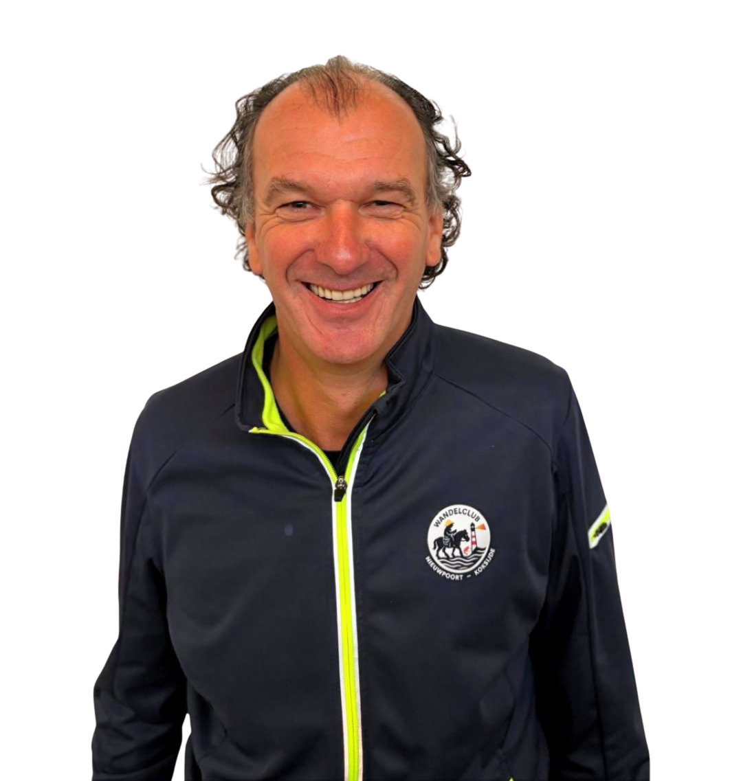 Man die glimlachend in een zwart jack staat, met een logo van een wandelclub op de borst.