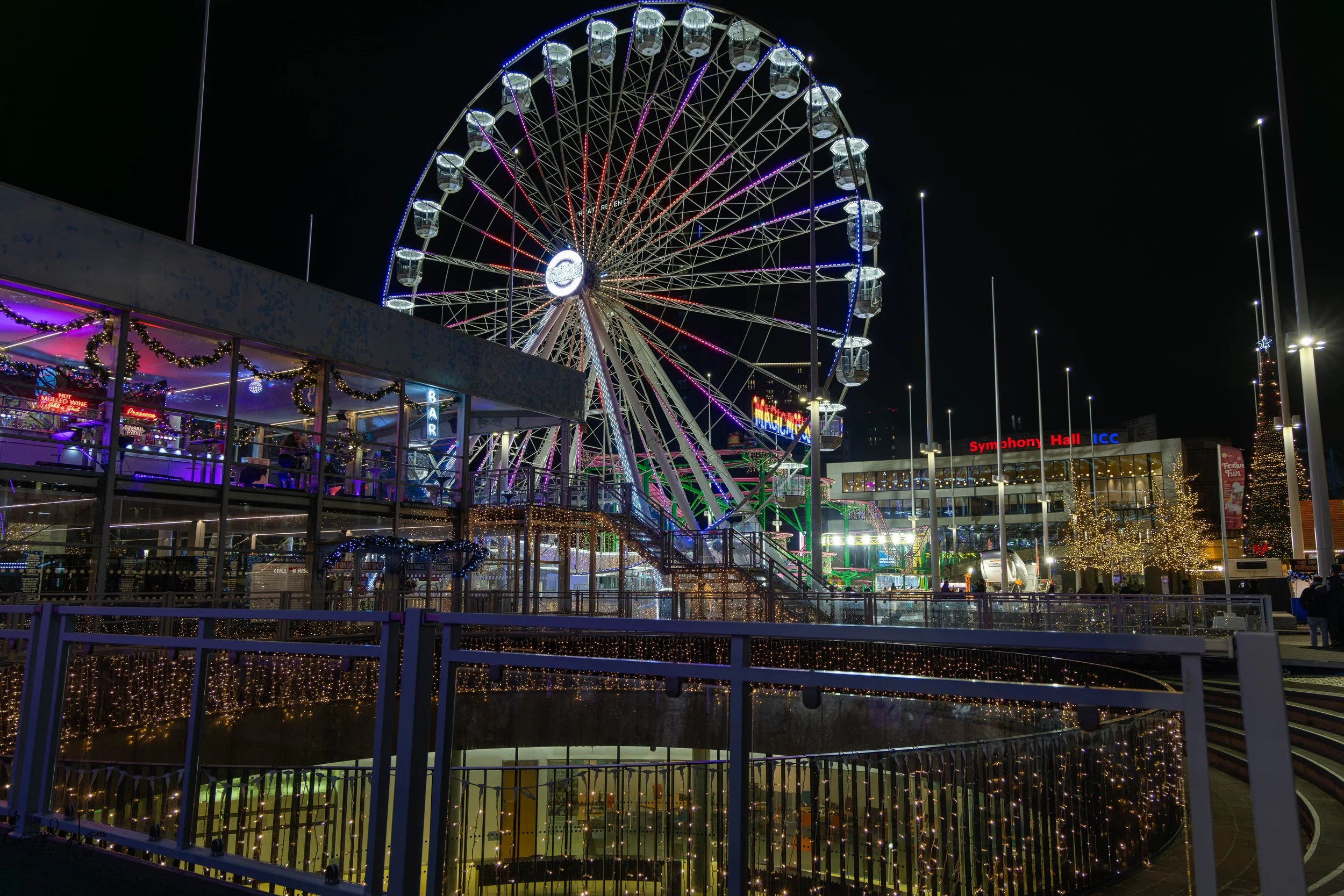 Ferris wheel glowing against the city night sky