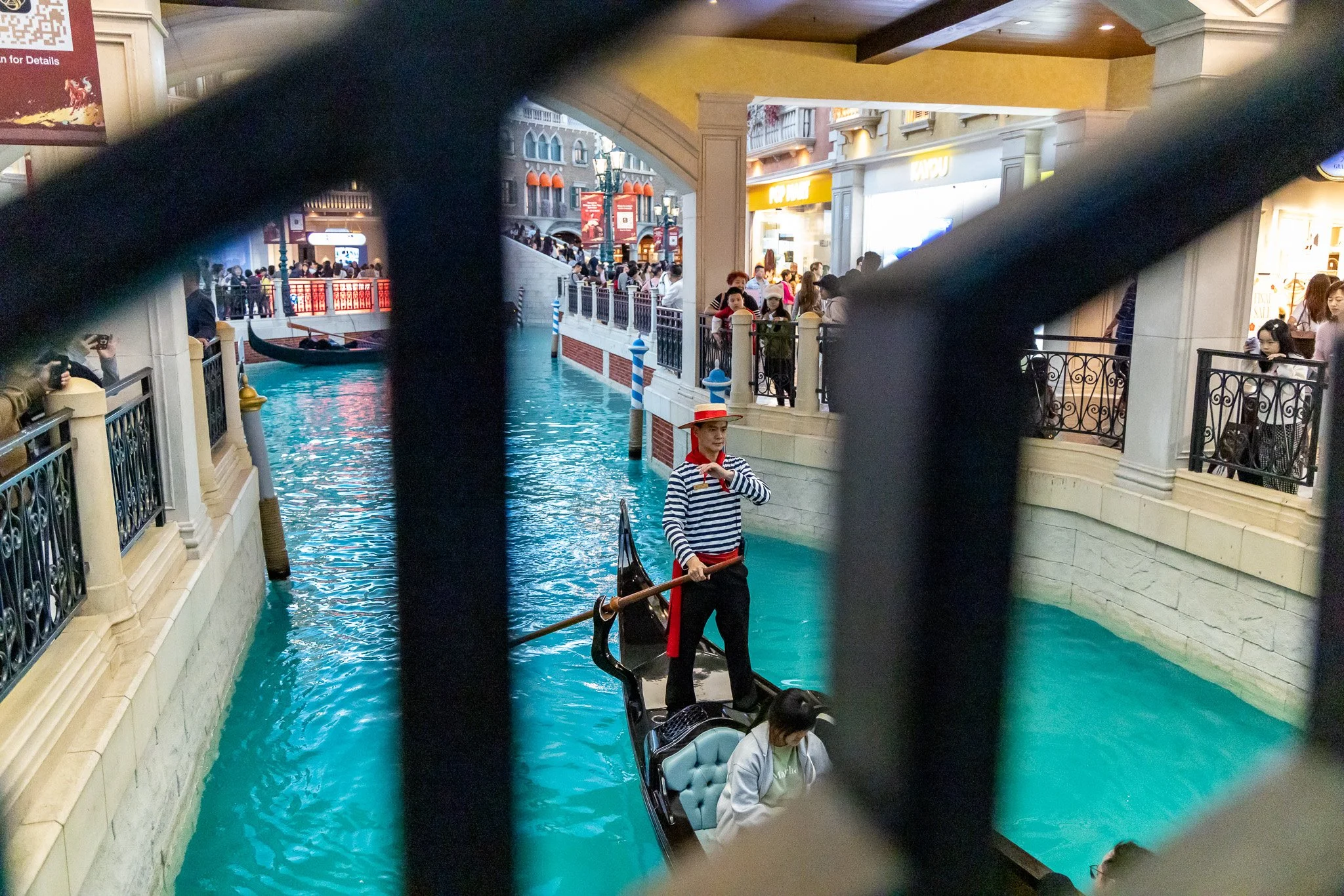 Gondola ride inside a shopping mall with crowded walkways and storefronts.