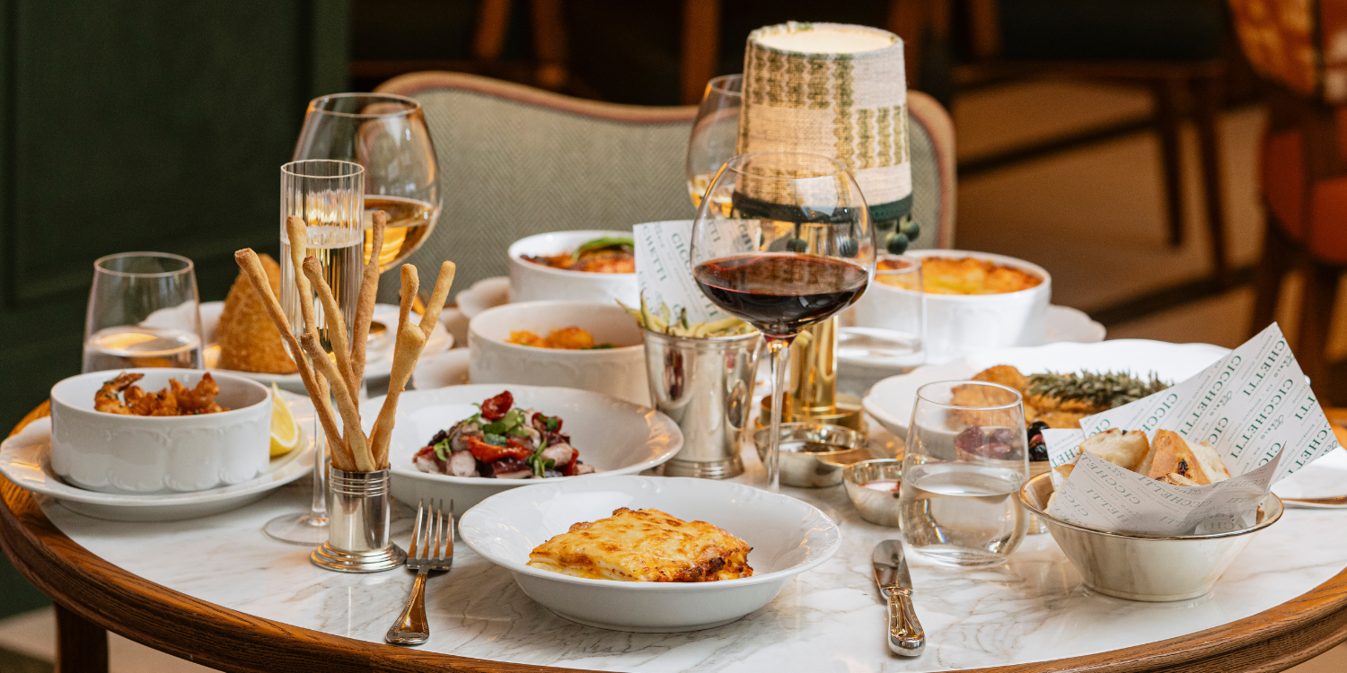 Repas français avec plusieurs plats, verres de vin rouge et blanc, table en marbre, ambiance chaleureuse.
