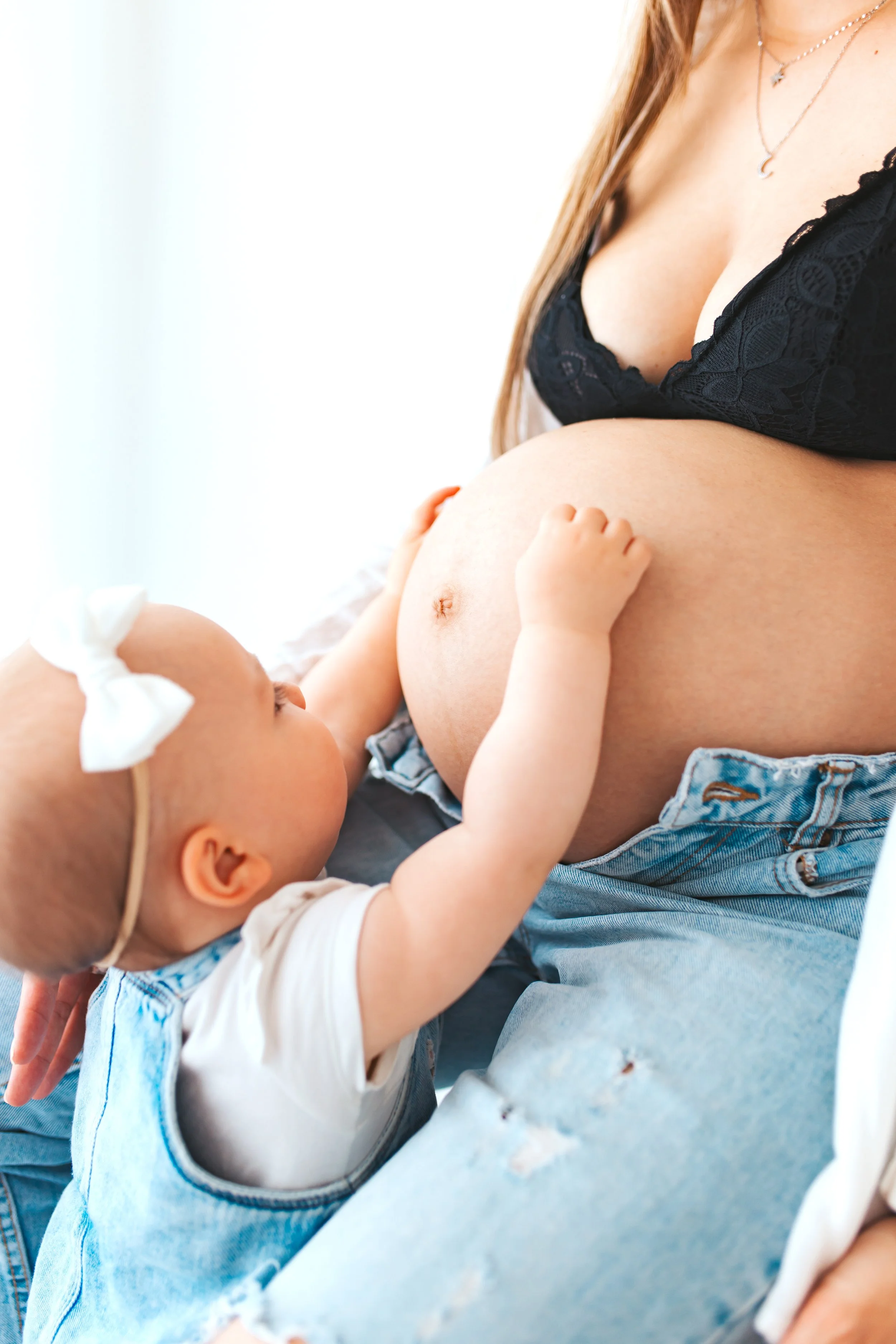 Eine schwangere Frau mit einem Baby, das die Brust zum Stillen hält.