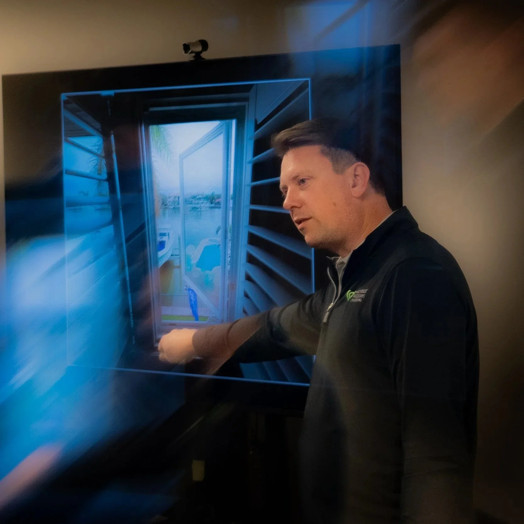 A man in a black jacket standing next to a large screen display showing an architectural rendering of a doorway with open doors and shelves on each side.