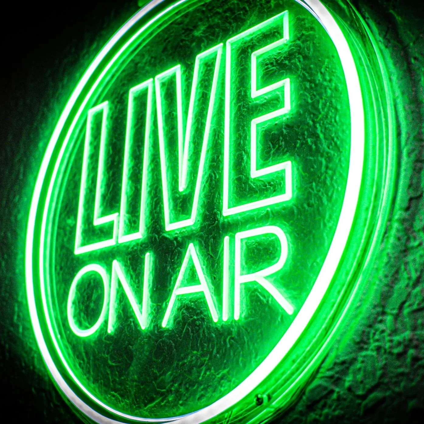 Green neon LED sign reading "LIVE ON AIR" mounted on a textured wall.