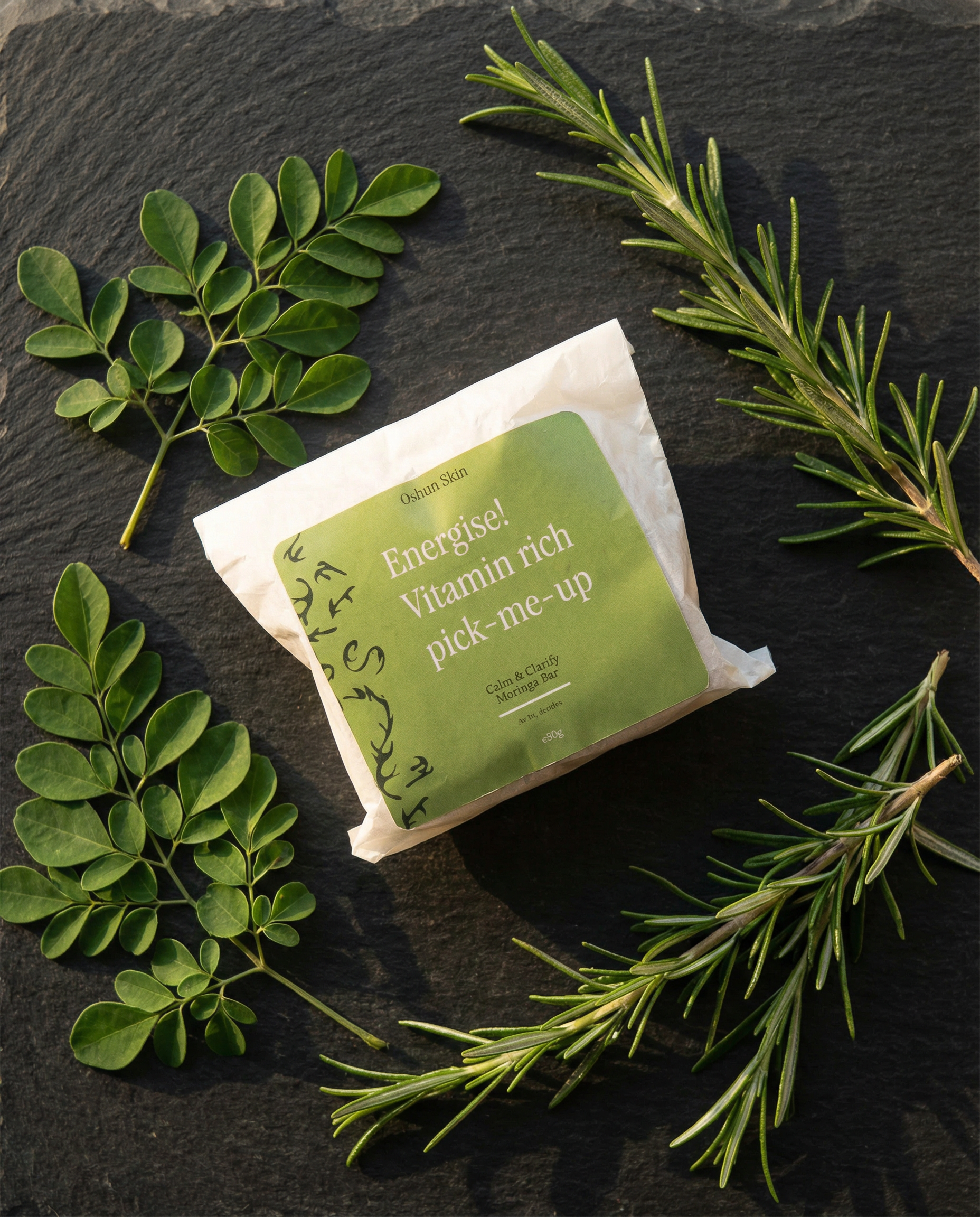 moringa bar packaging overhead shot with sprigs of rosemary and moringa leaf.png