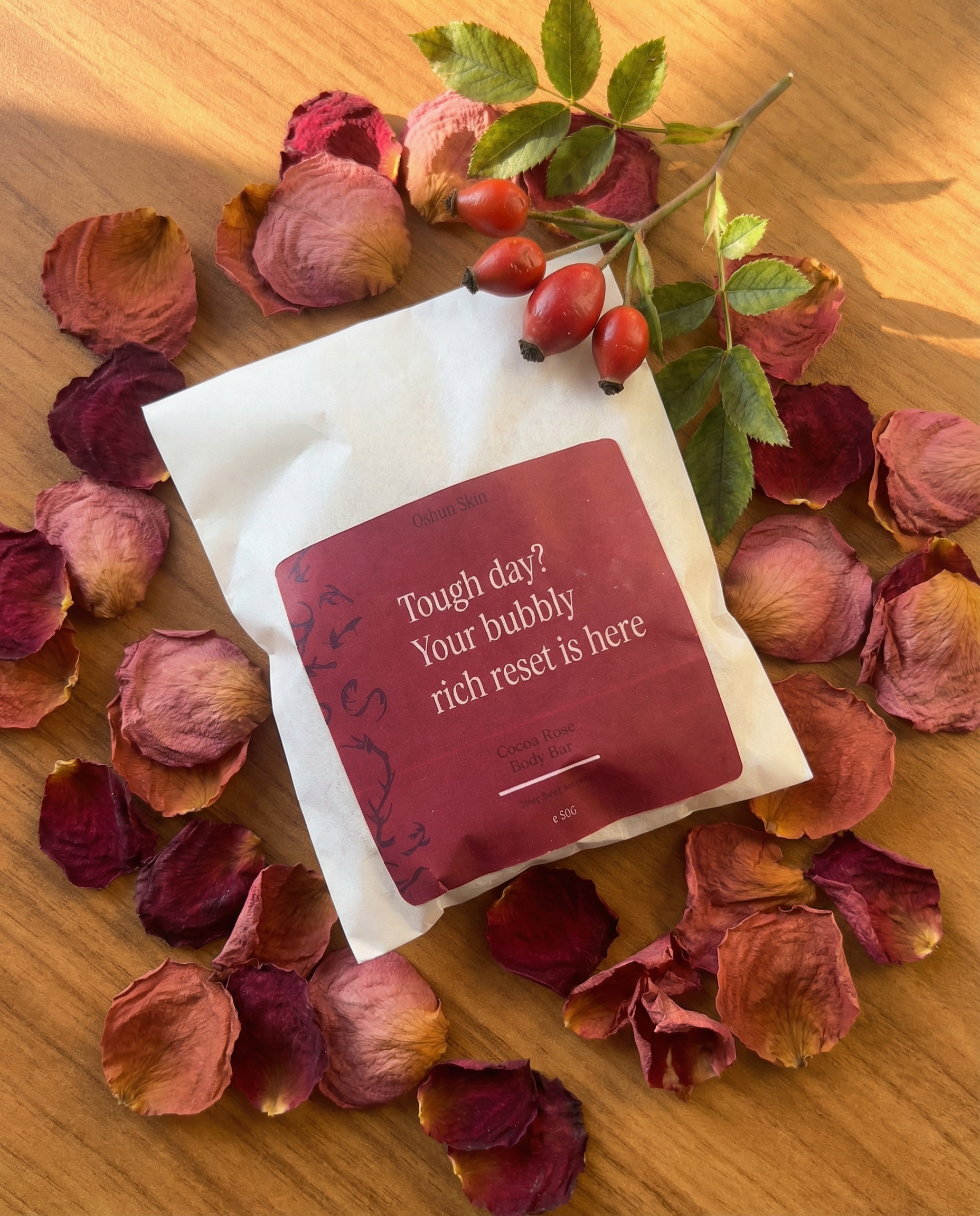 cocoa rose packaging surrounded by dried rose petals and a rosehip sprig on a.png