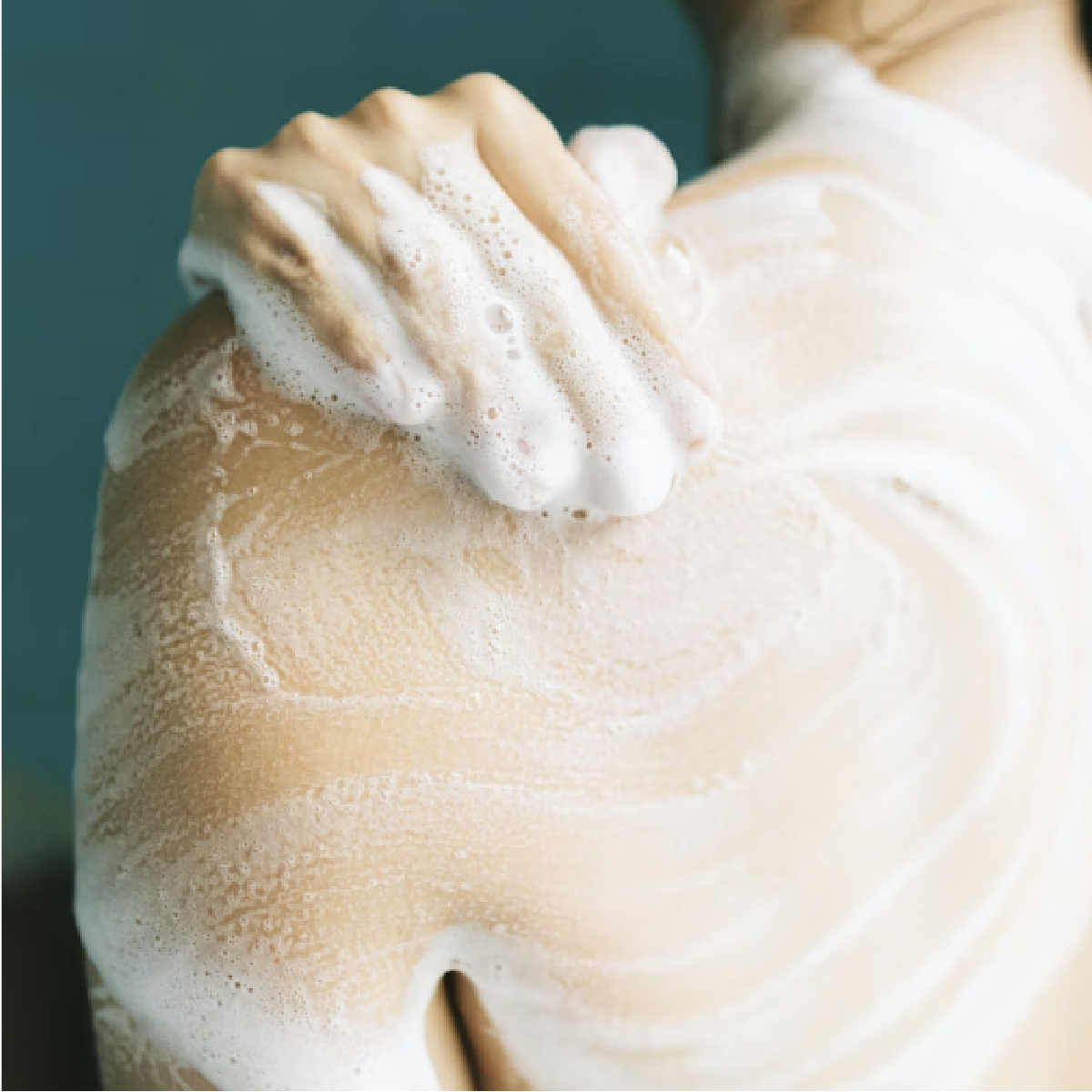 A shot of a woman's back in the shower with creamy lathered bubbles