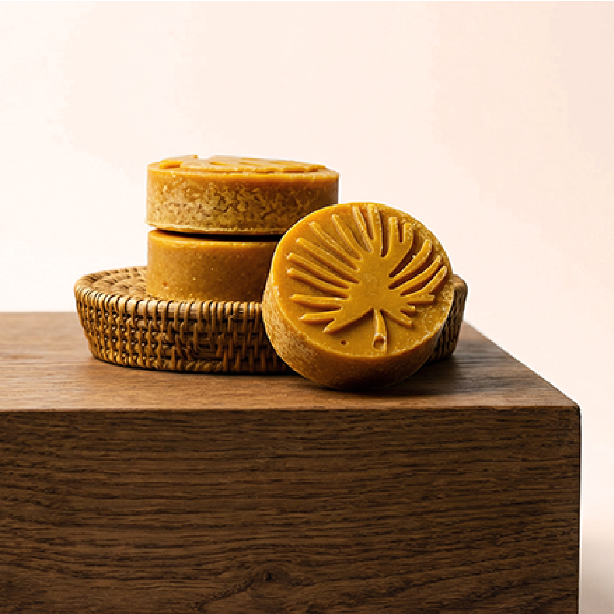 A stacked set of three turmeric bars on a brown counter, cream sunlit background and a botanical design on a bar facing