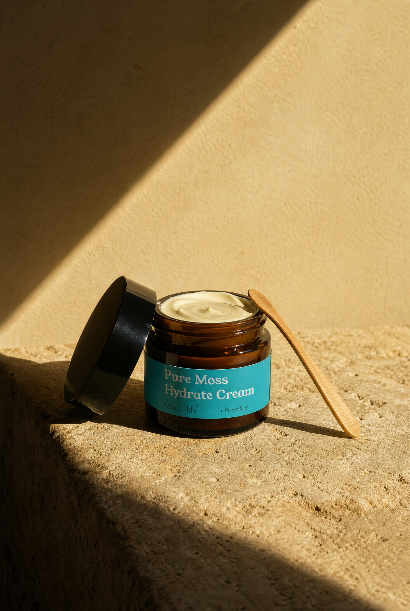 Open jar of sea moss moisturiser on warm sandy stone surface with bamboo scoop