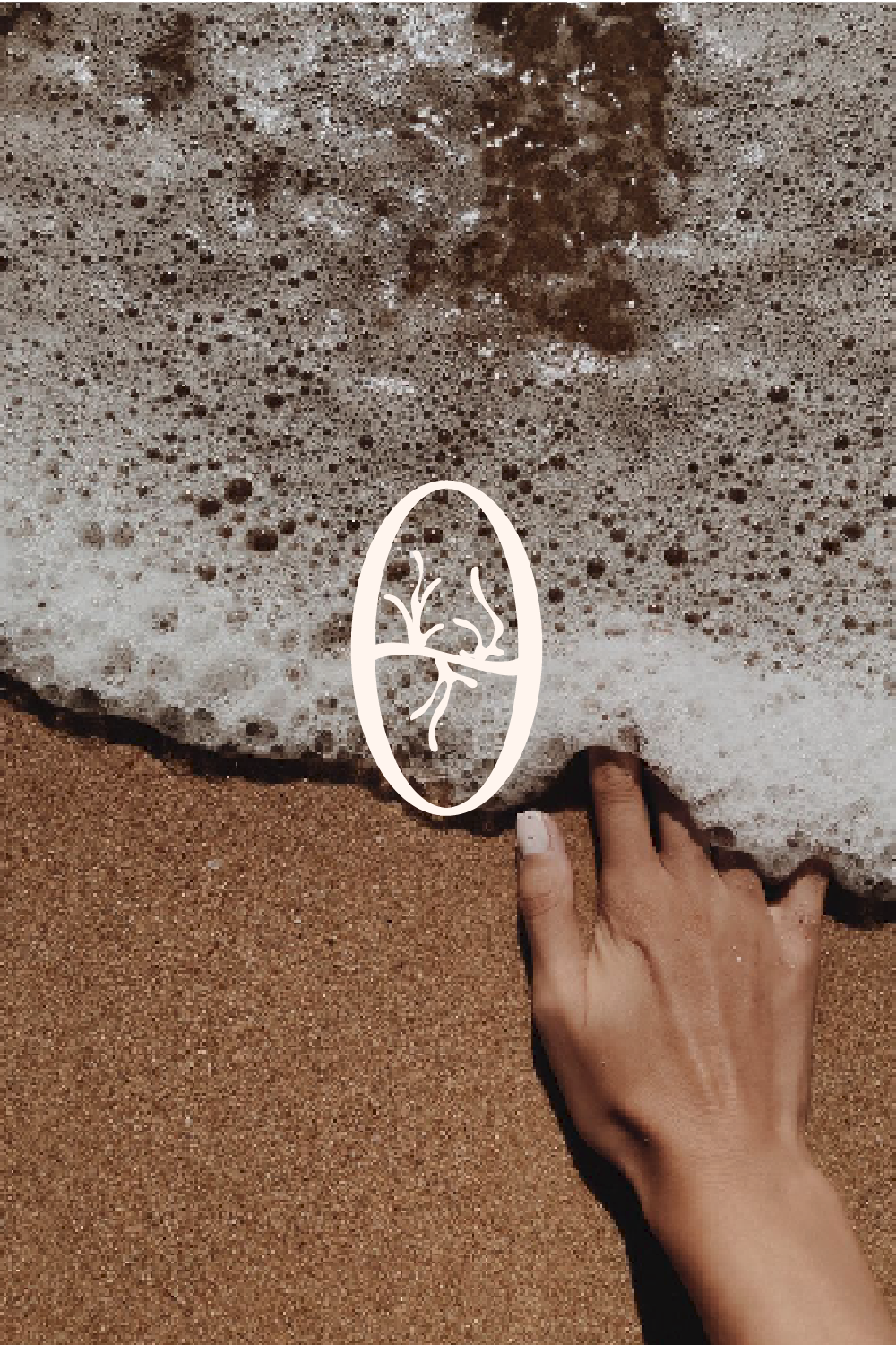 A hand touching wet sand and ocean foam on the beach, with a small wave approaching the shore.