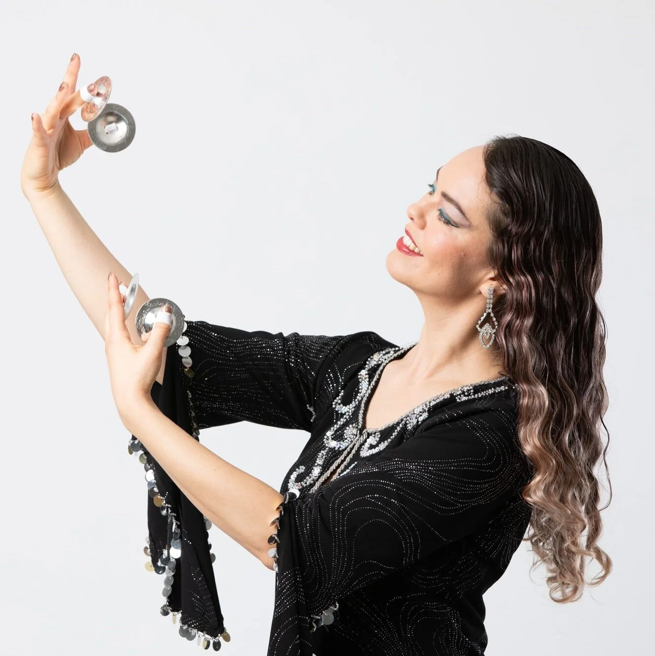 Juniper Nichols in a black and silver Egyptian galabeya playing sagat, also known as finger cymbals.