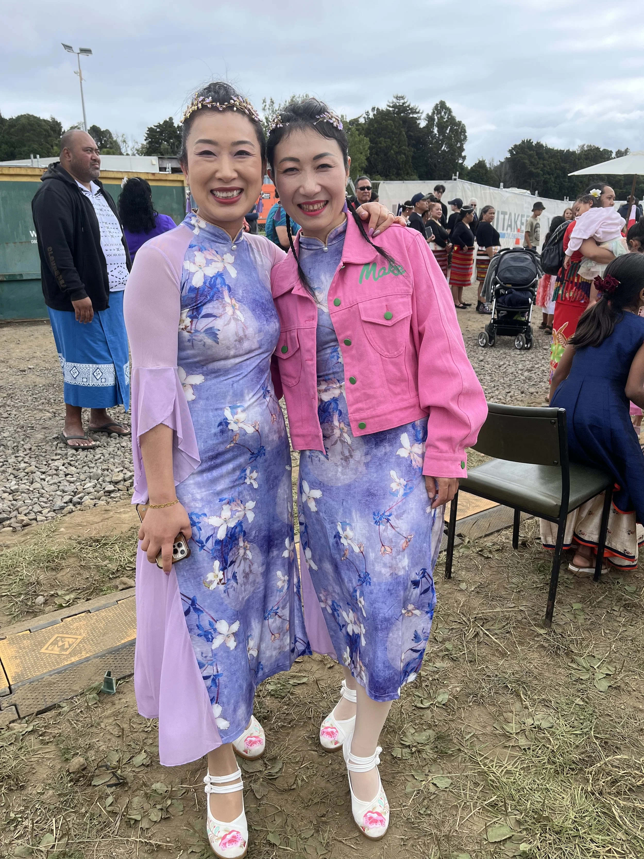 Chinese dancers Amy and Hui at the Multiethnic Extravaganza in traditional cherry blossom-patterned hanbok dresses and floral headpieces.