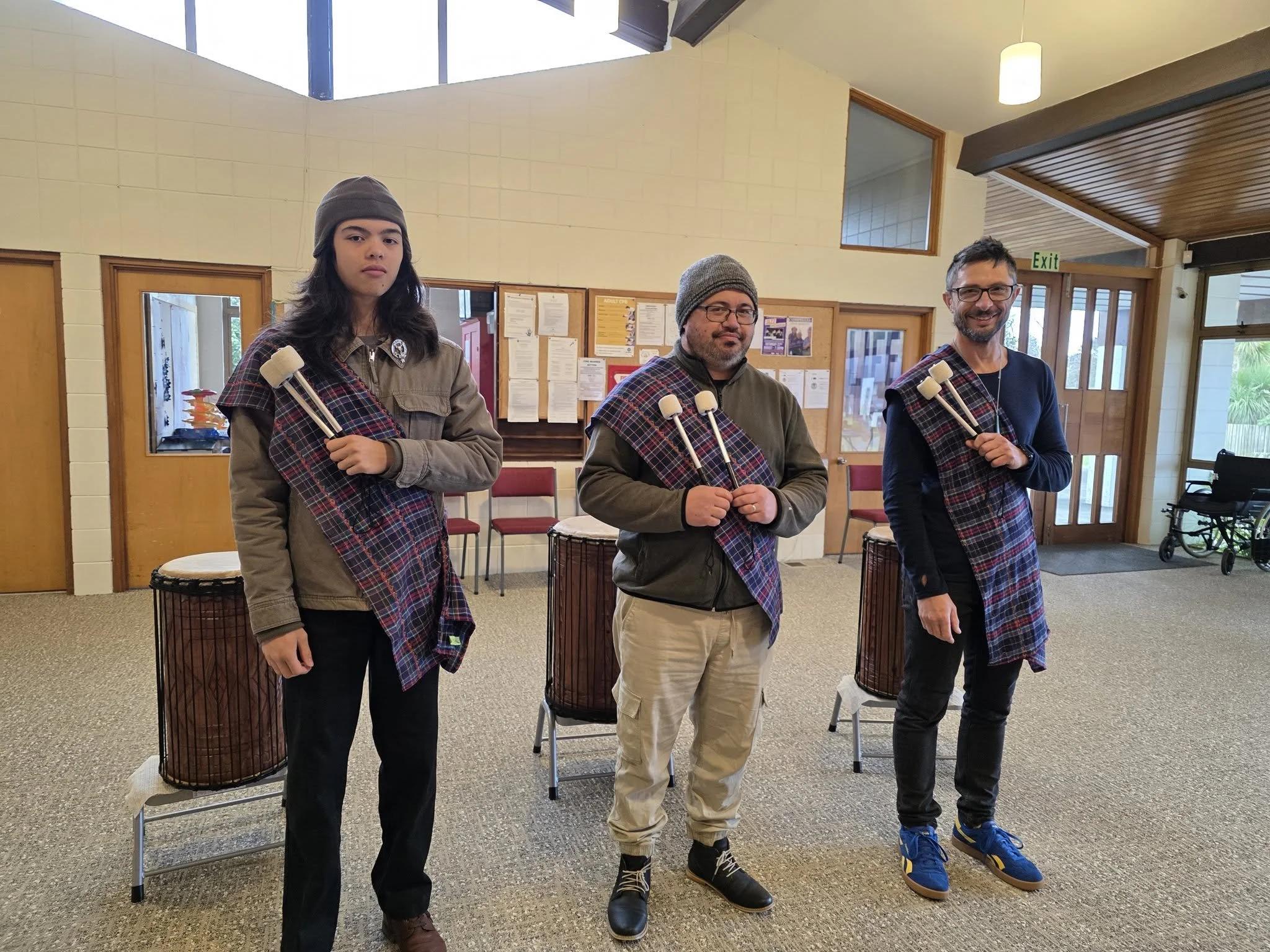 Members of AFINCA wearing tartan and holding drumsticks for their Ya Bassa rehearsal