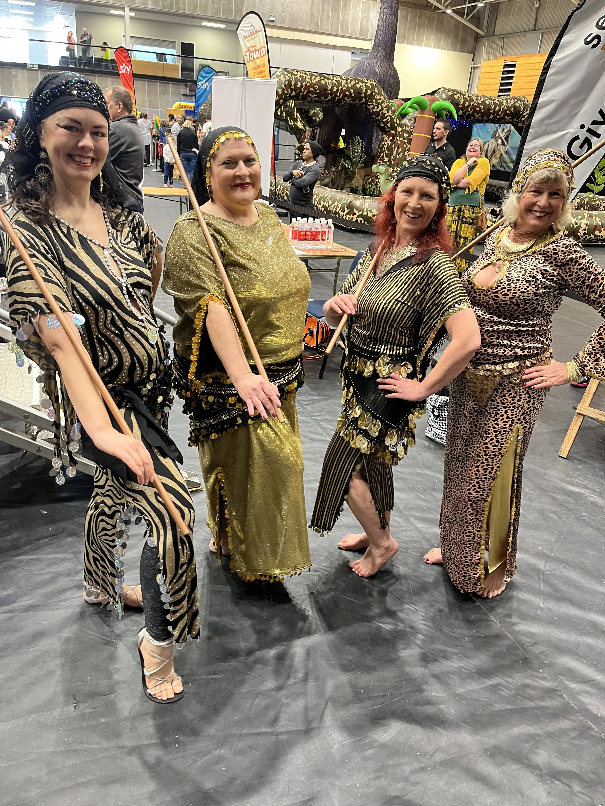 Juniper and the Gems dressed in animal print and gold costumes, posing with assaya (sticks) for their folkloric Egyptian dance at the Special Children's Extravaganza in Taranaki.