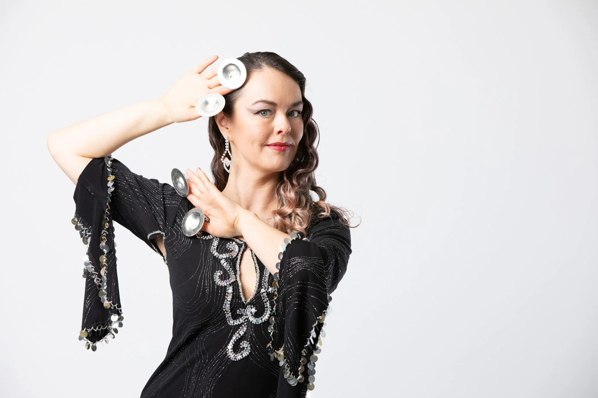 Juniper Nichols poses in a black galabeya with silver finger cymbals