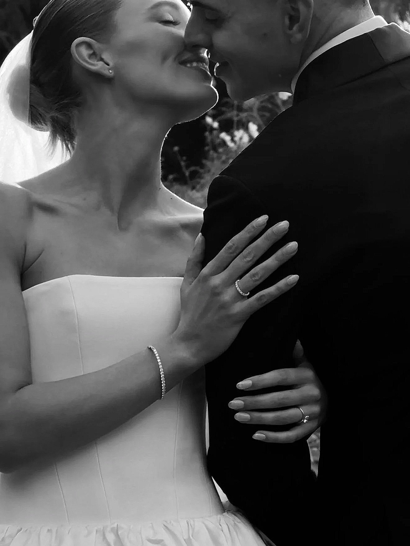 Black and white photo of a bride and groom sharing a close, intimate moment, with their foreheads touching and eyes closed, both smiling gently.
