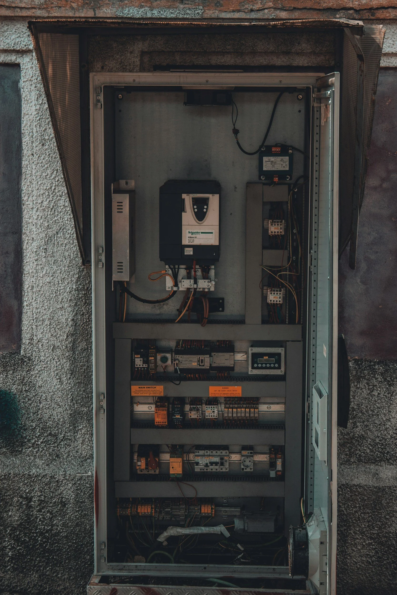 View of an open industrial electrical control panel with various switches, relays, and electronic components.