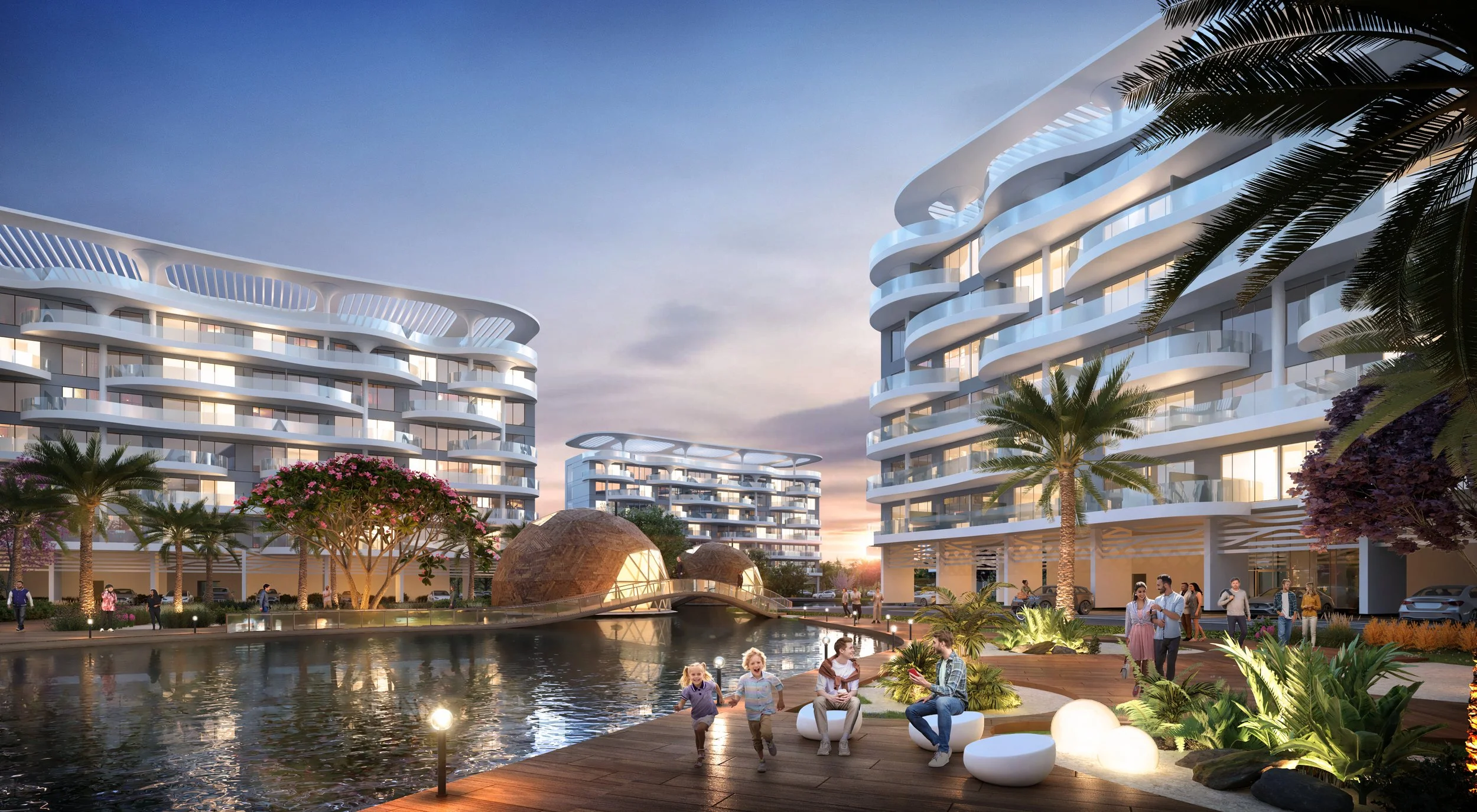 Modern residential complex with curved white balconies, a water feature, palm trees, and people enjoying the outdoor space during sunset