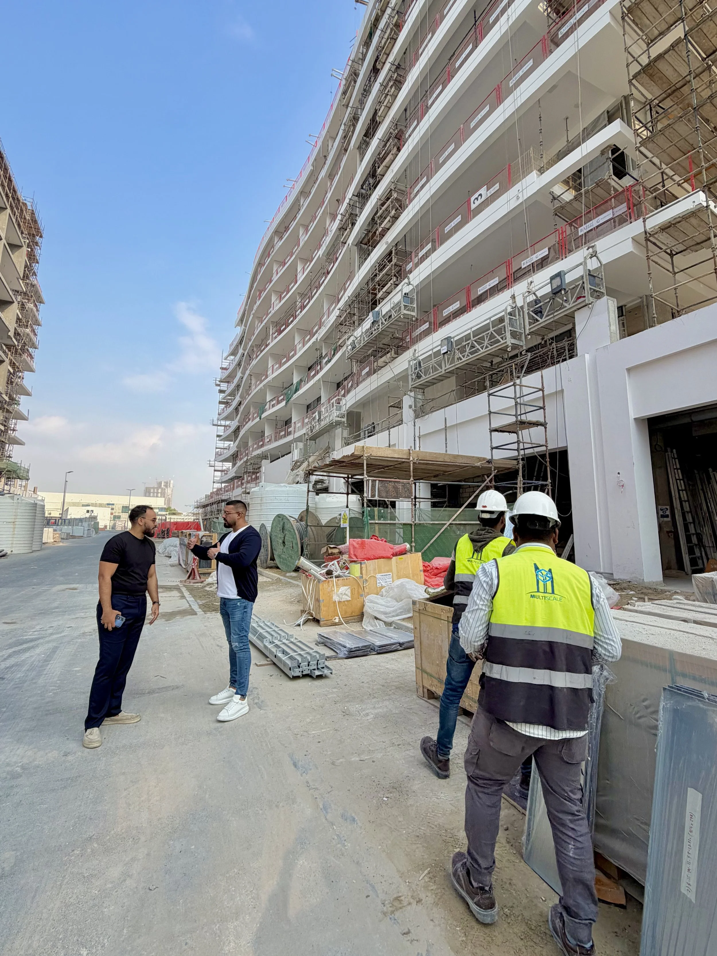 Construction site on a high-rise building with workers and two men in discussion.