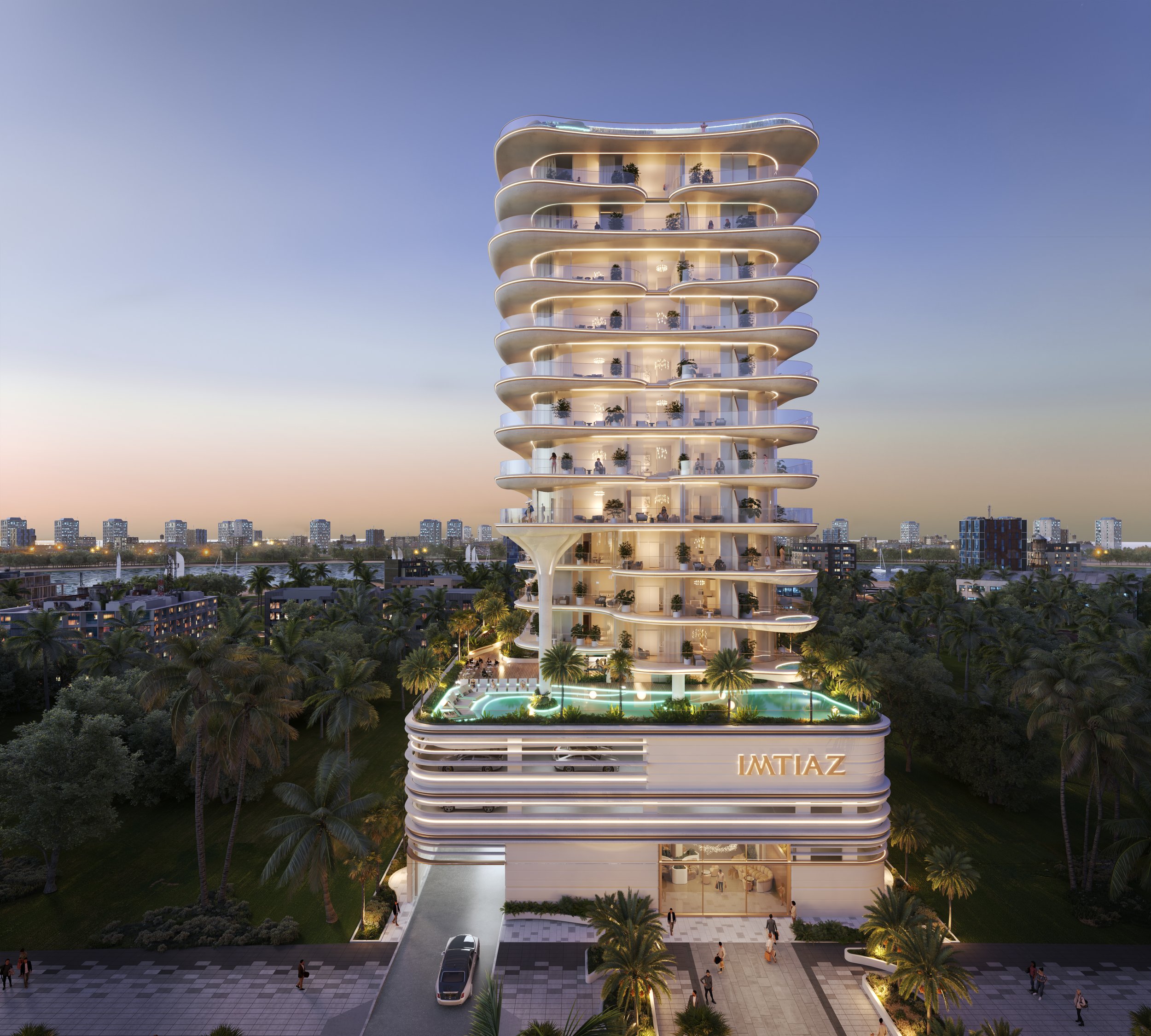 A modern high-rise residential building with curved balconies and glass railings, surrounded by palm trees and a pool area, with the name 'IMTIAZ' on the base. Cityscape visible in the background at dusk.