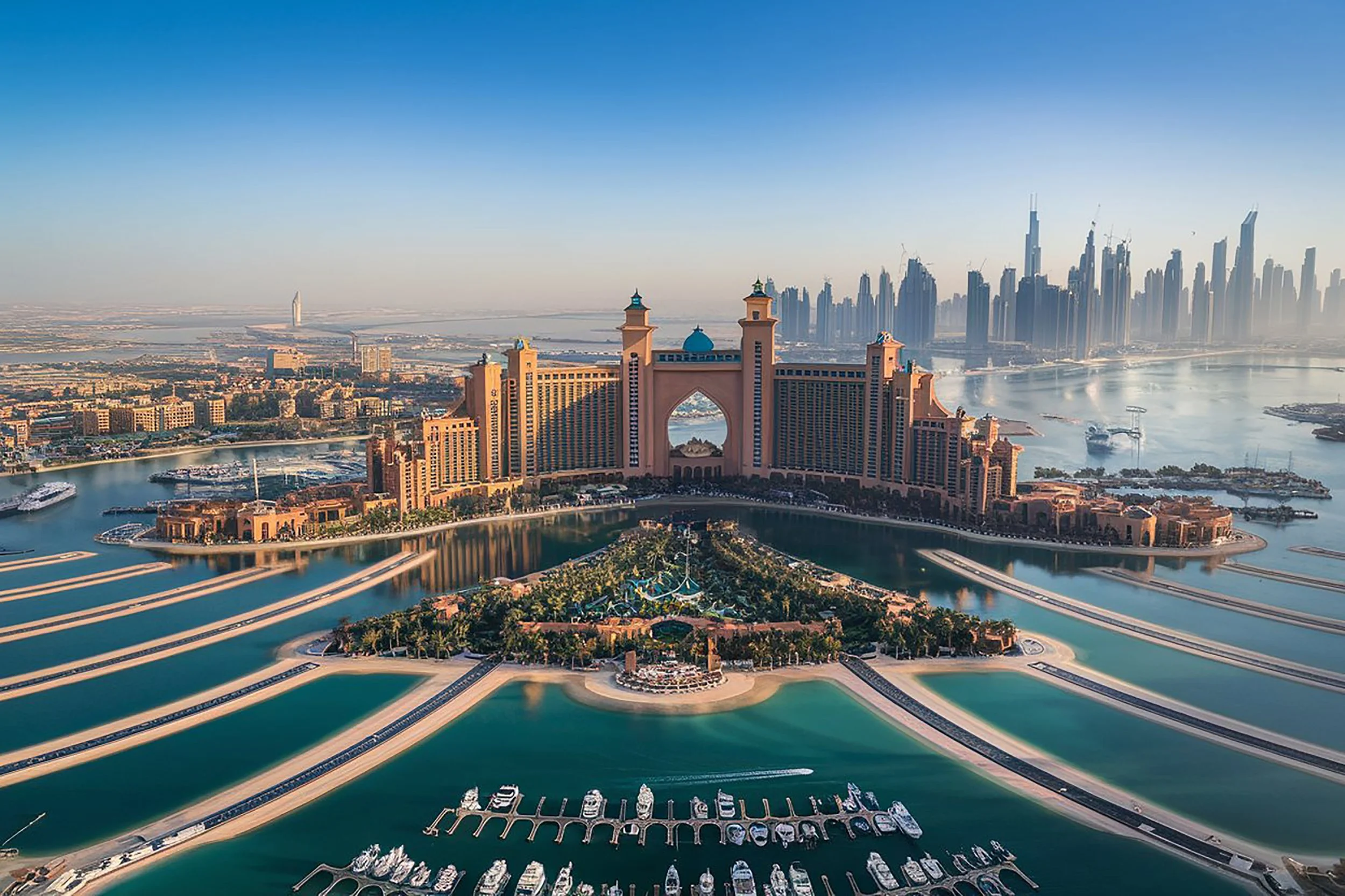 Aerial view of the Atlantis The Palm hotel and the Dubai skyline with tall skyscrapers in the background, surrounded by water.