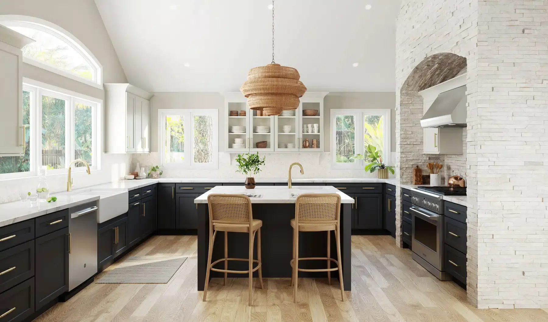 Modern kitchen with black lower cabinets, white upper cabinets, and a central island with a white marble countertop and two beige wicker barstools. Large windows let in natural light, and a white brick wall features a built-in oven and range hood. Rattan pendant light hangs above the island, and potted greenery decorates the space.