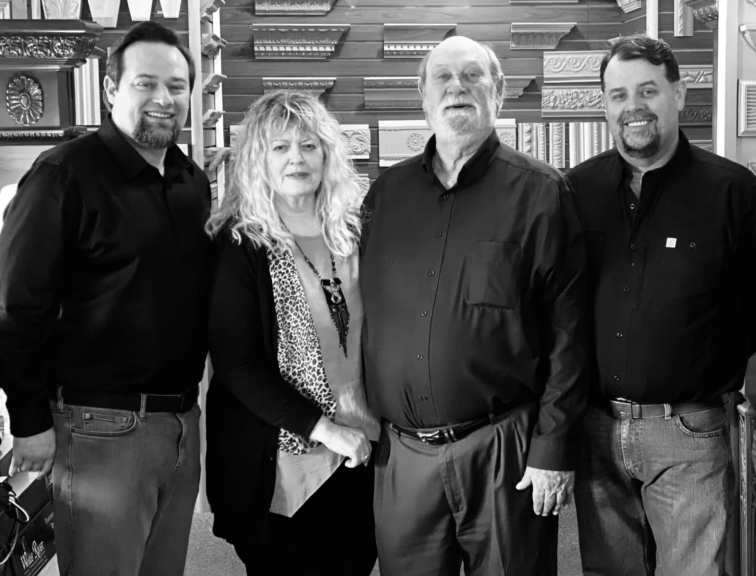 Bruce and Joan Johnson, founders of White River Hardwoods, pictured with their sons inside the company's showroom alongside examples of their craftsmanship.