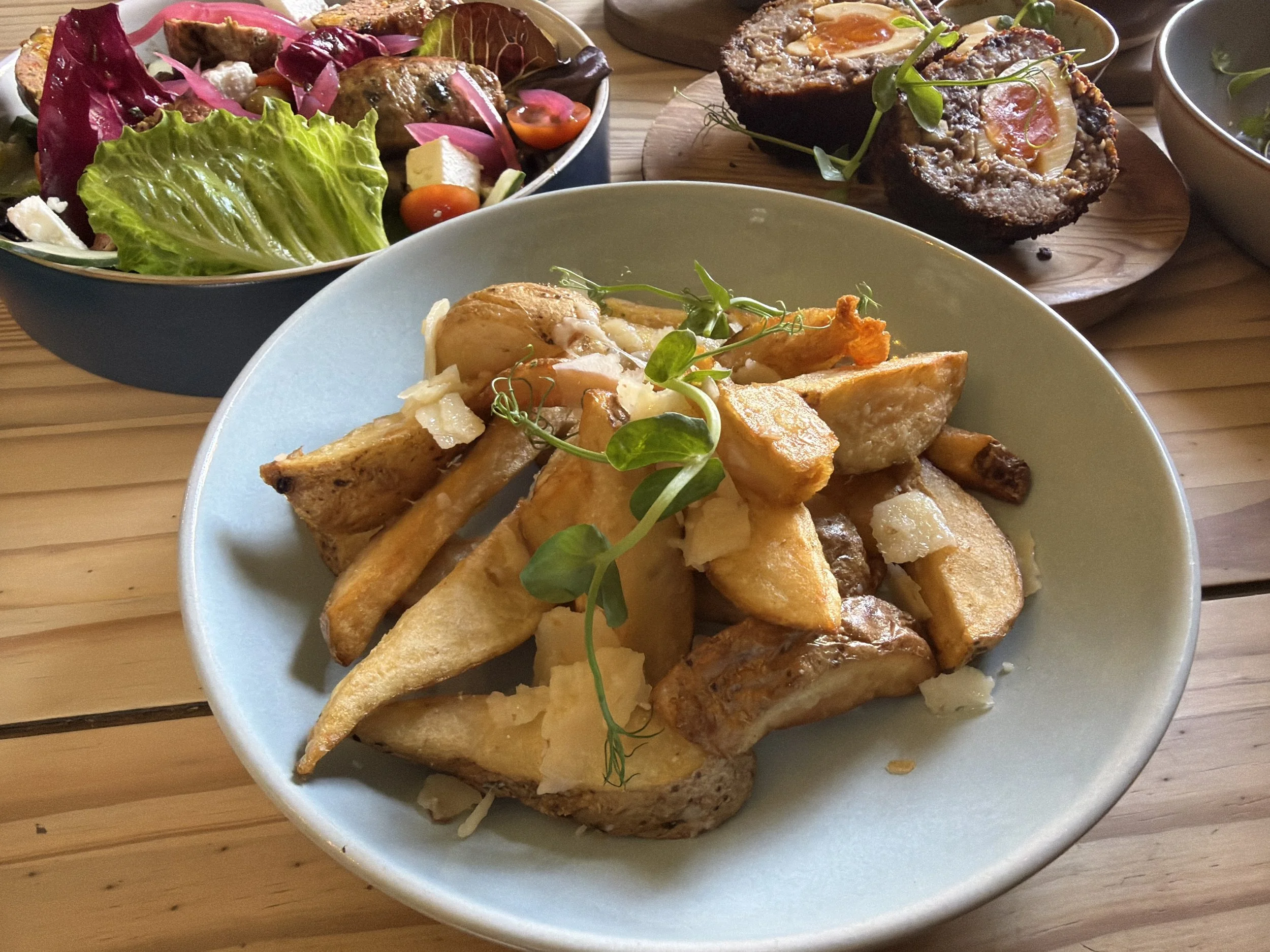 A plate of French fries topped with melting cheese and garnished with microgreens.