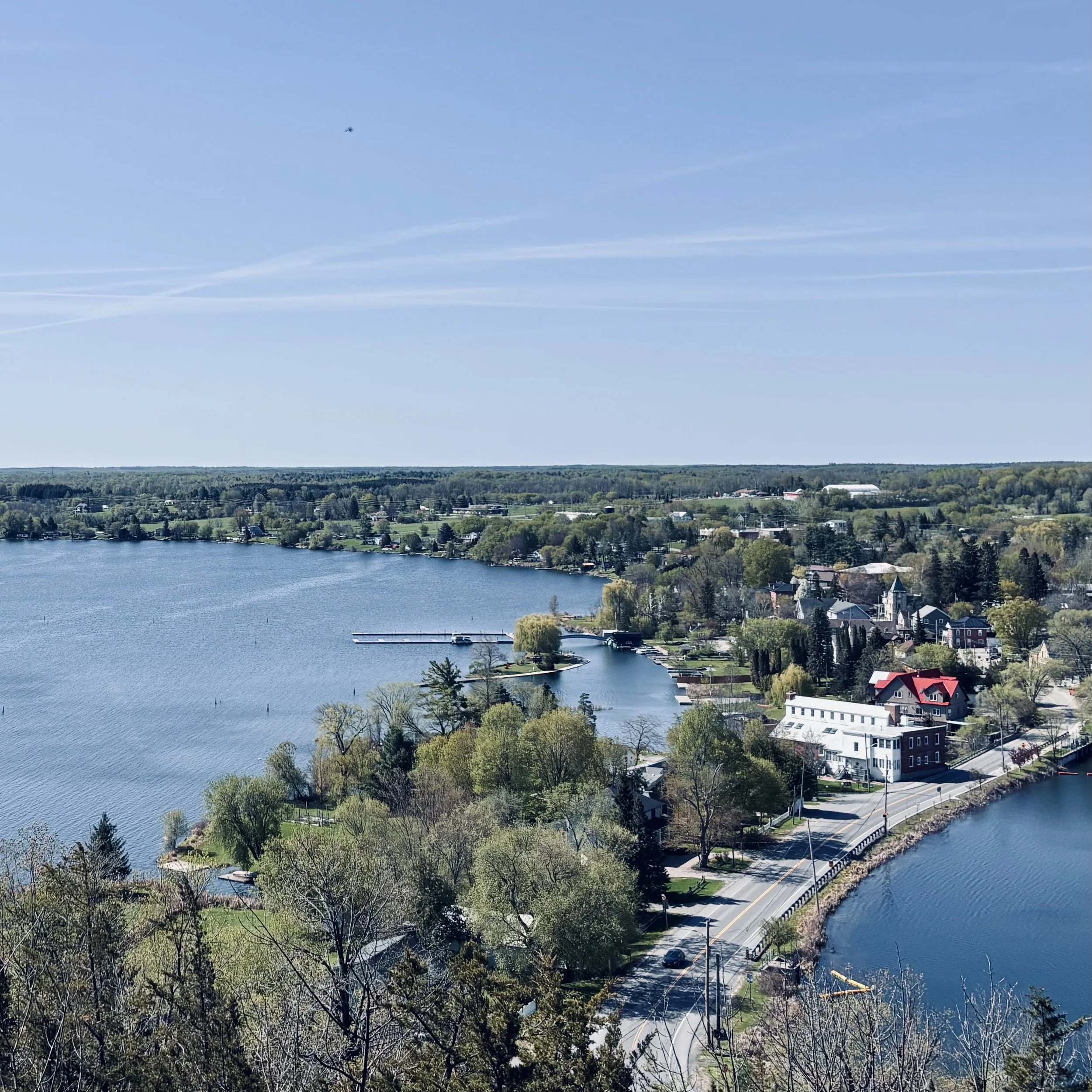 A birds eye view of the village of Westport, featuring views of Upper Rideau Lake and Westport Pond. Photo taken from Spy Rock Lookout at Foley Mountain Conservation Area in May 2025.