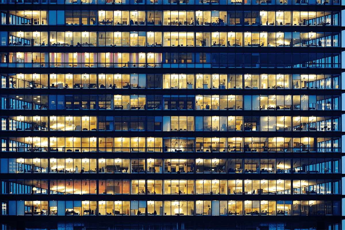 A worker in a yellow high-visibility jacket and white safety helmet operating electrical panels in an industrial setting.