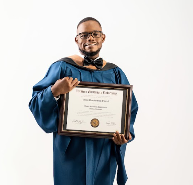 Graduate in blue cap and gown holding diploma from Western Governors University, smiling against a white background.