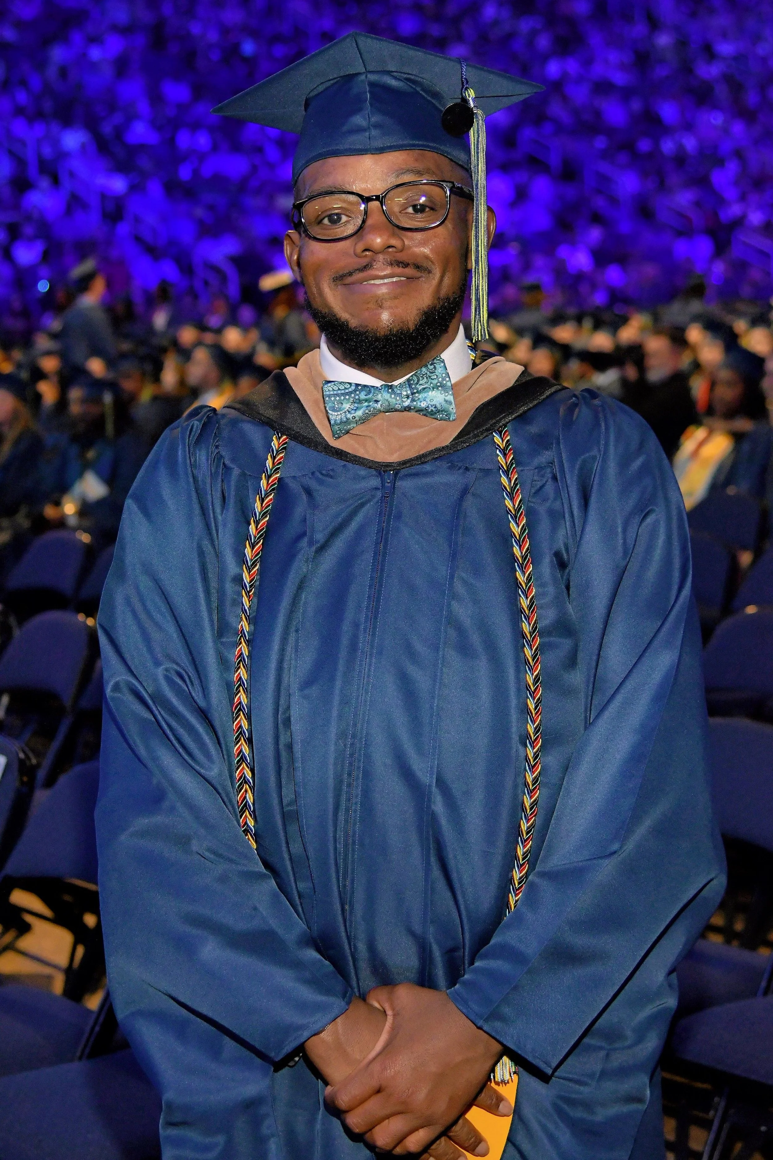 A man in graduation cap and gown smiling at a graduation ceremony.