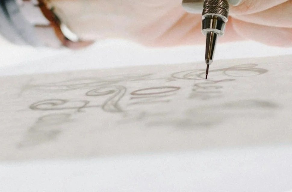 Close-up of a mechanical pencil drawing cursive writing on paper.