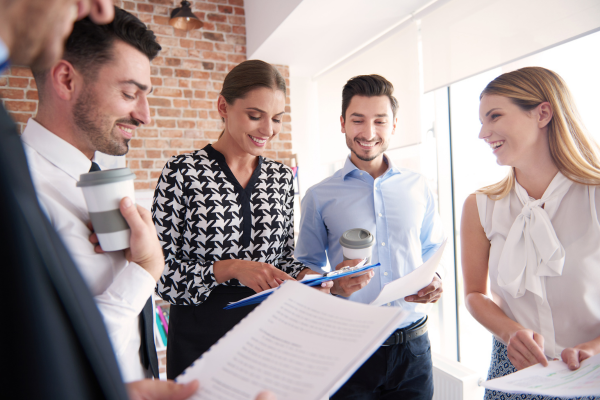 Diverse business team laughing and discussing documents during an informal meeting near a window