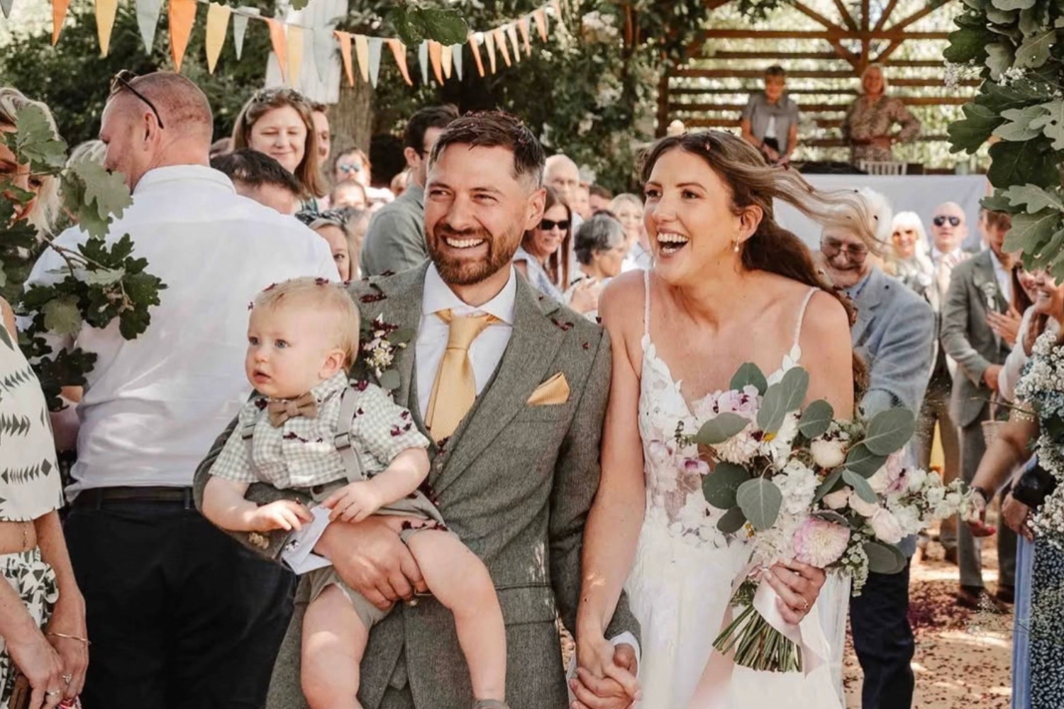 bride with a wild flower bouquet and groom with baby at festival inspired wedding 