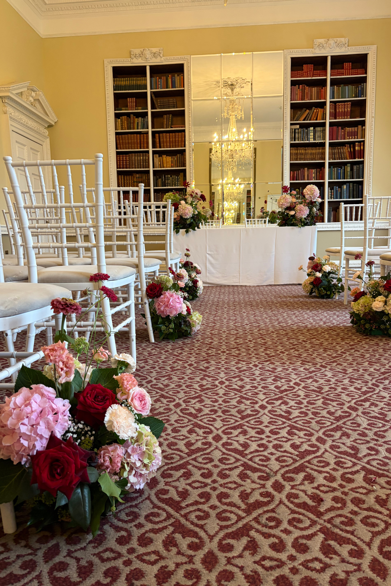 pink and burgundy wedding flowers as aisle end displays in the Library at Buxted Park Hotel Sussex