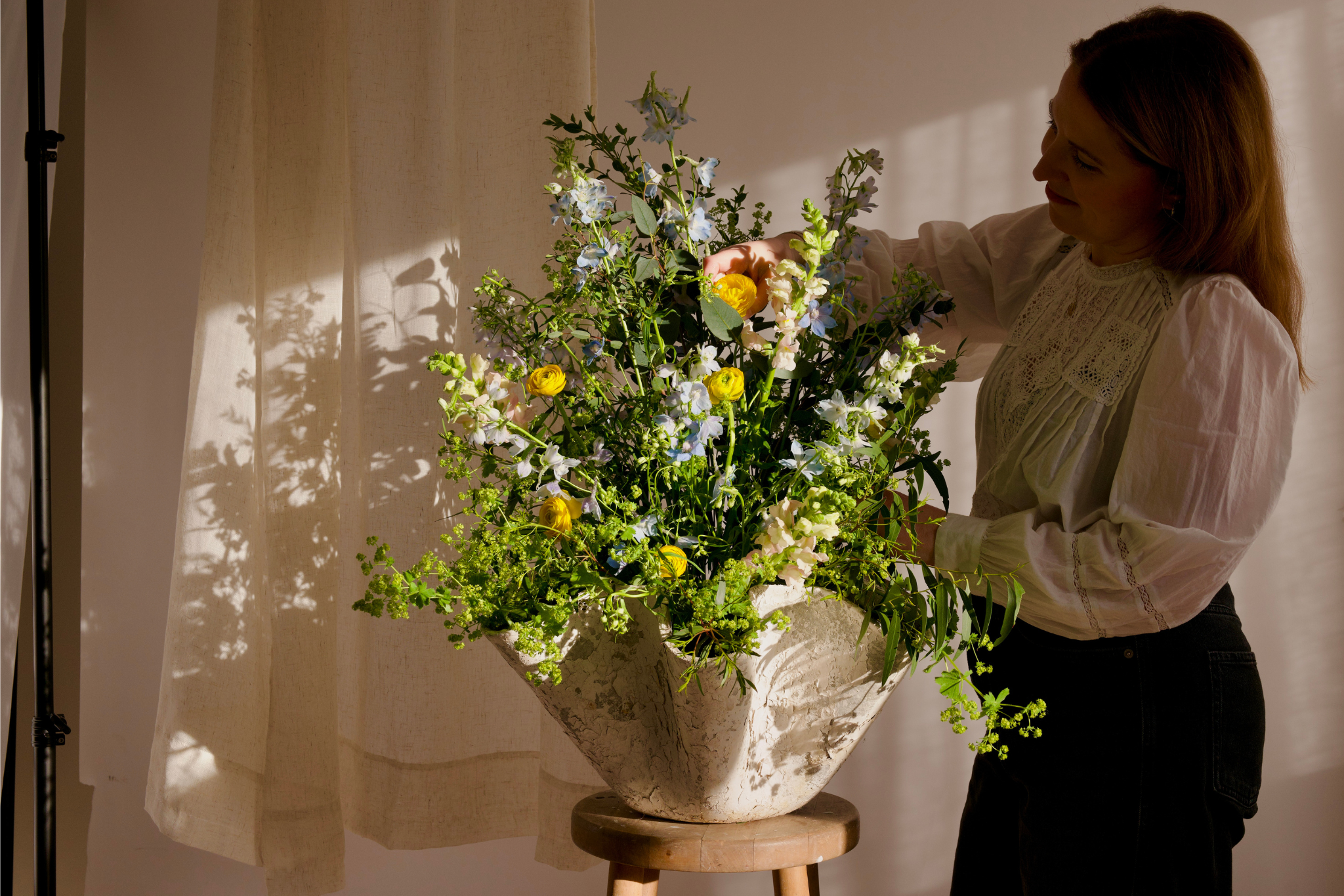 florist styling a Willy Guhl planter with blue and yellow flowers