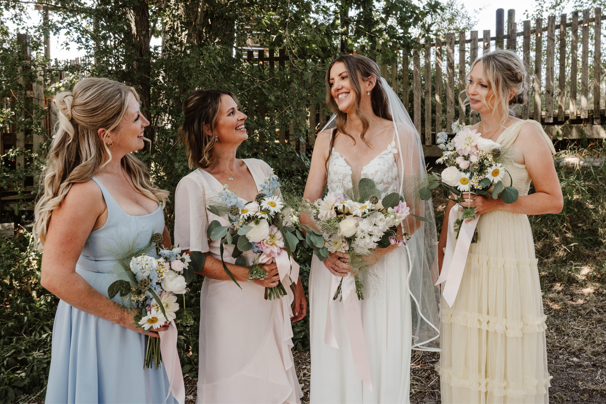 A bride with 3 bridesmaids carrying wild flower bouquets for a festival themed wedding in Sussex