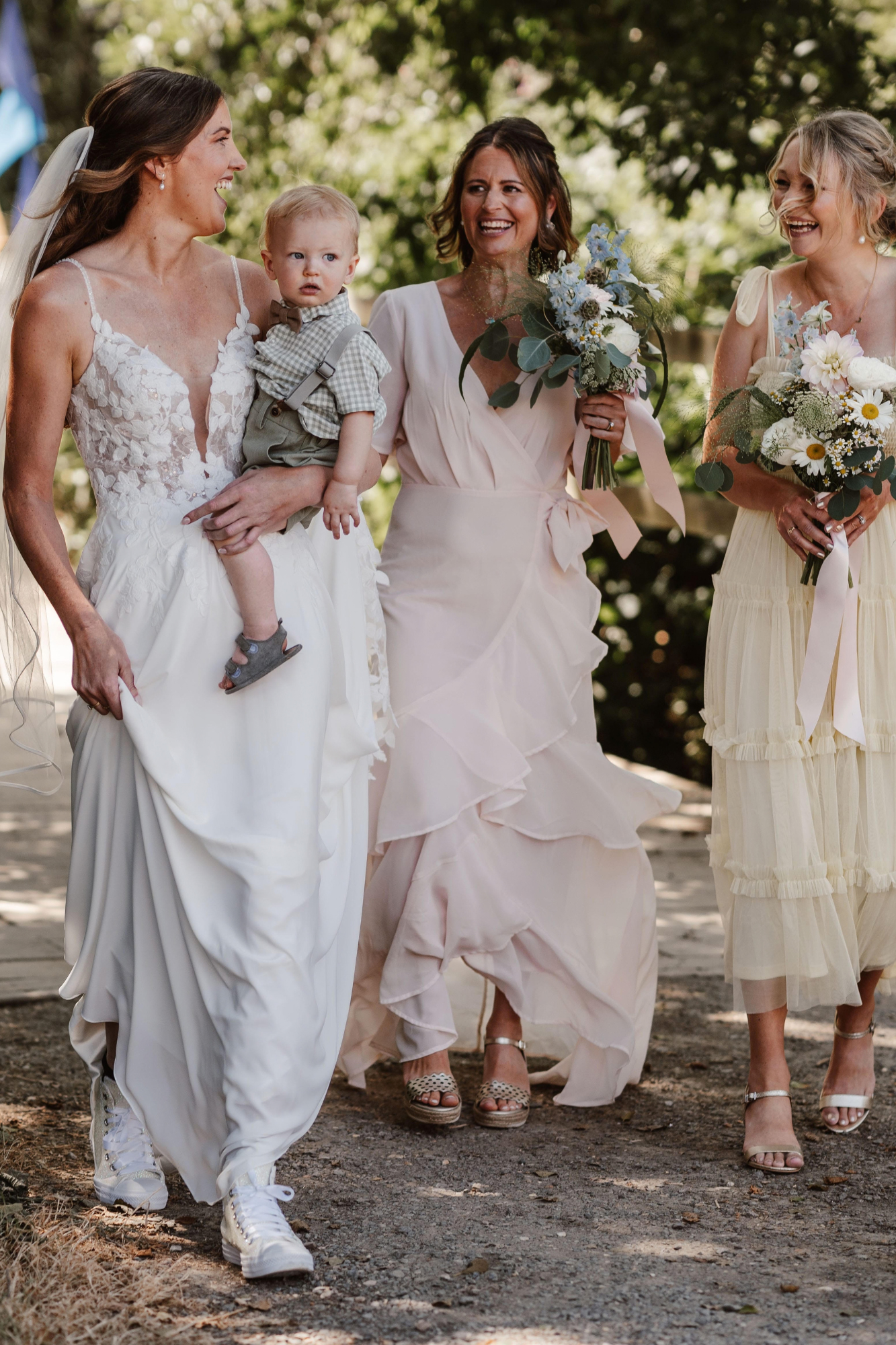 A bride walking with her bridesmaids who are carrying wild flower inspired bouquets for a festival wedding in Sussex