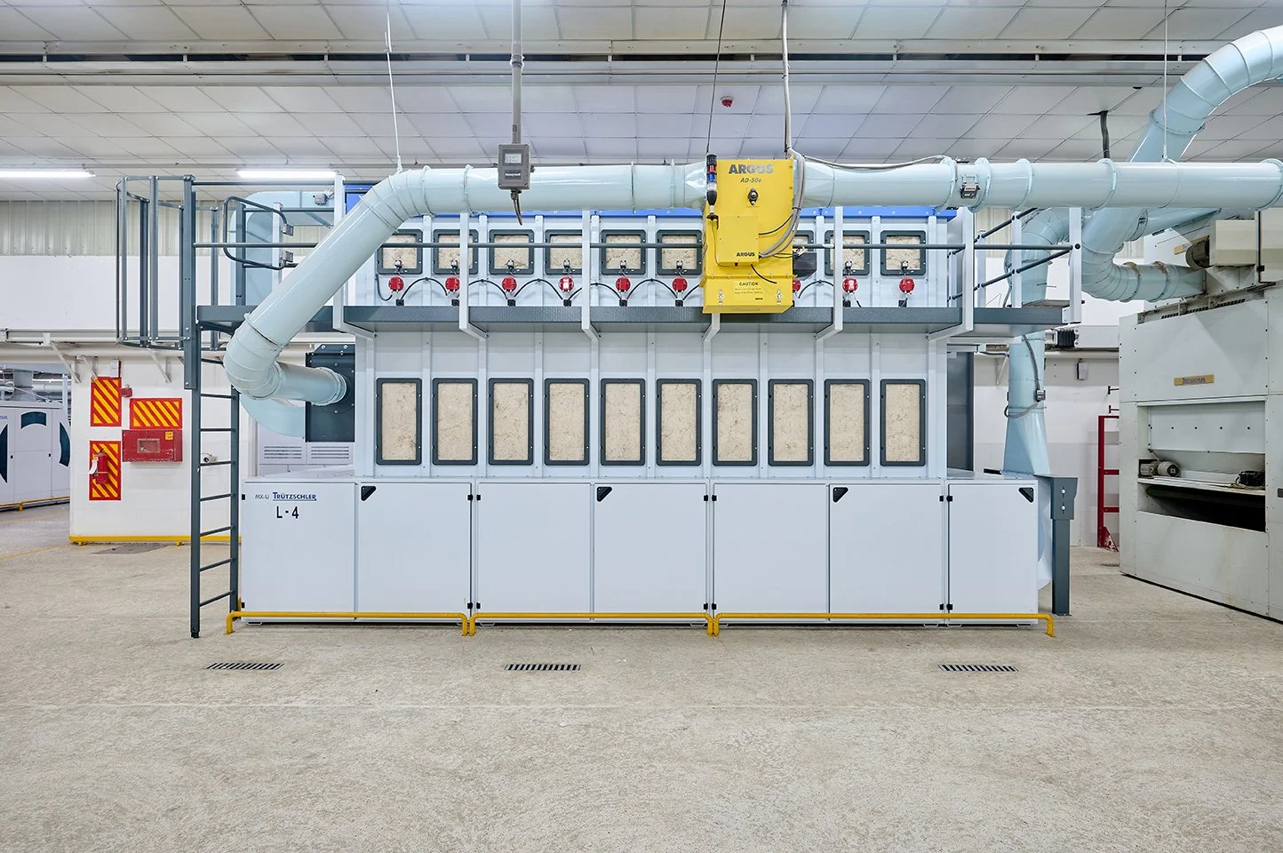 Industrial filtration system with large white metal equipment, multiple cylindrical filters, and large ducts and pipes in a clean factory setting.